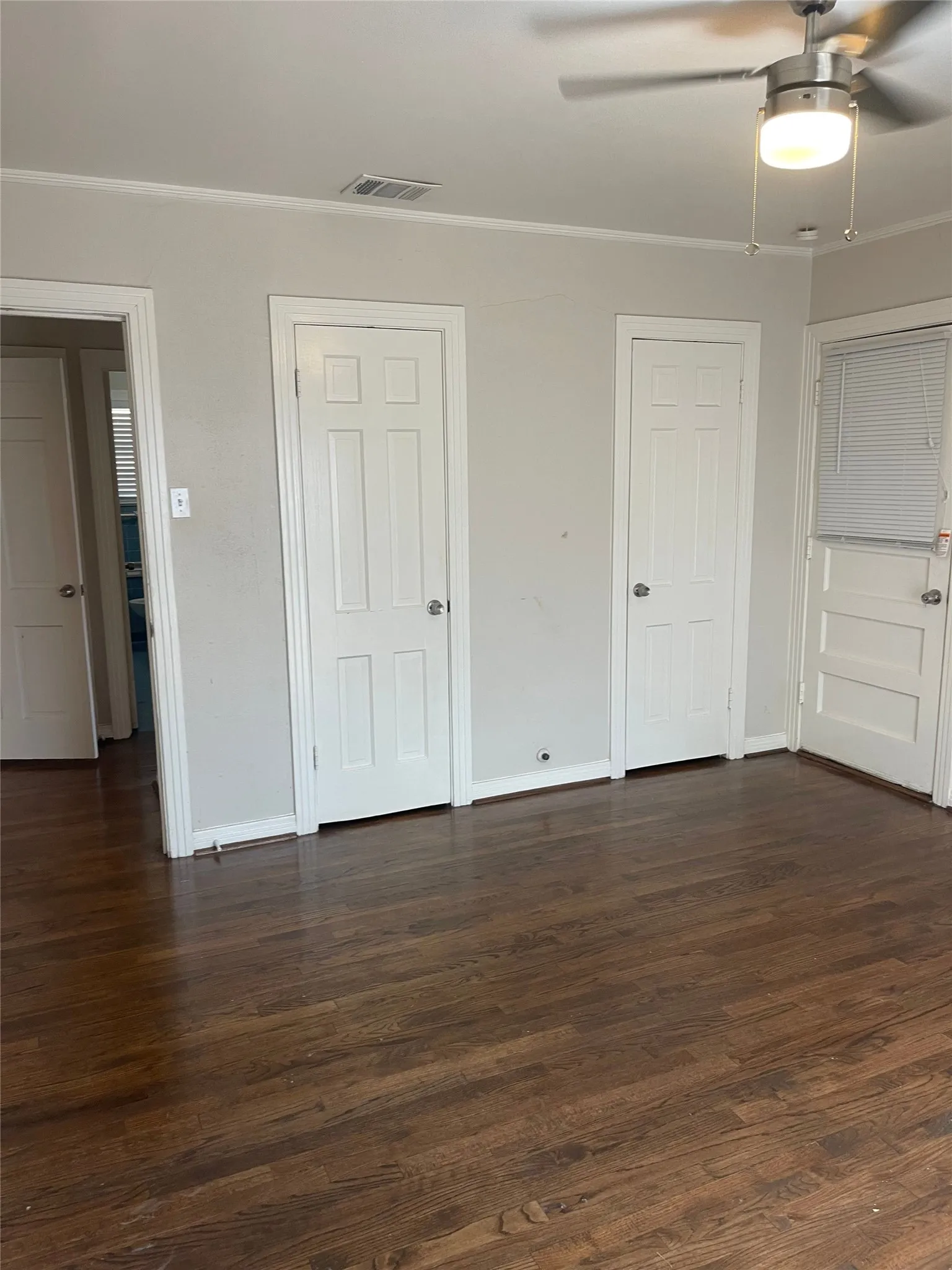 Hardwood-style flooring, contemporary ceiling fan with integrated lighting, white trim, and multiple panel doors