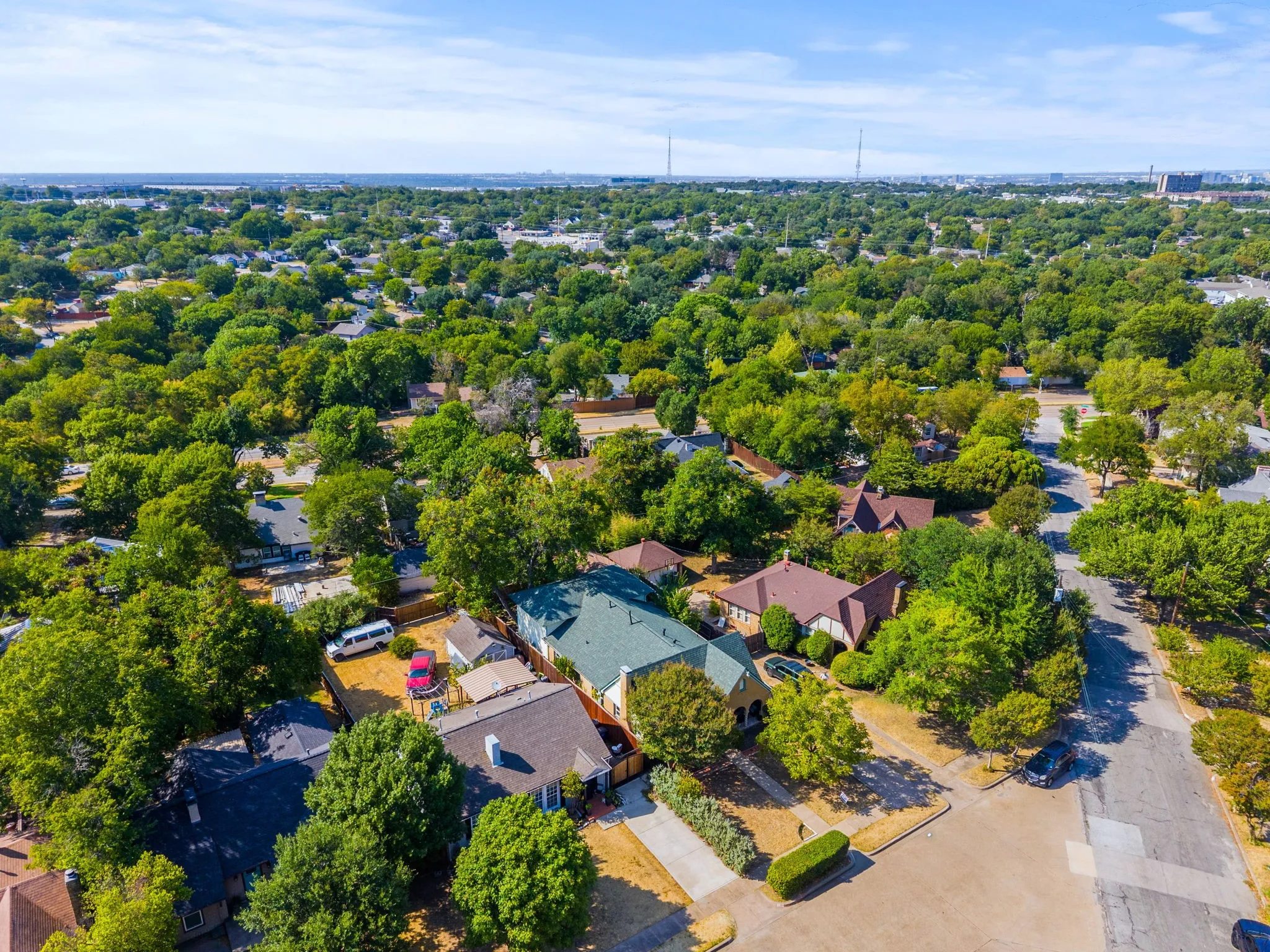 Aerial perspective showcasing the residential street, mature trees, and numerous properties