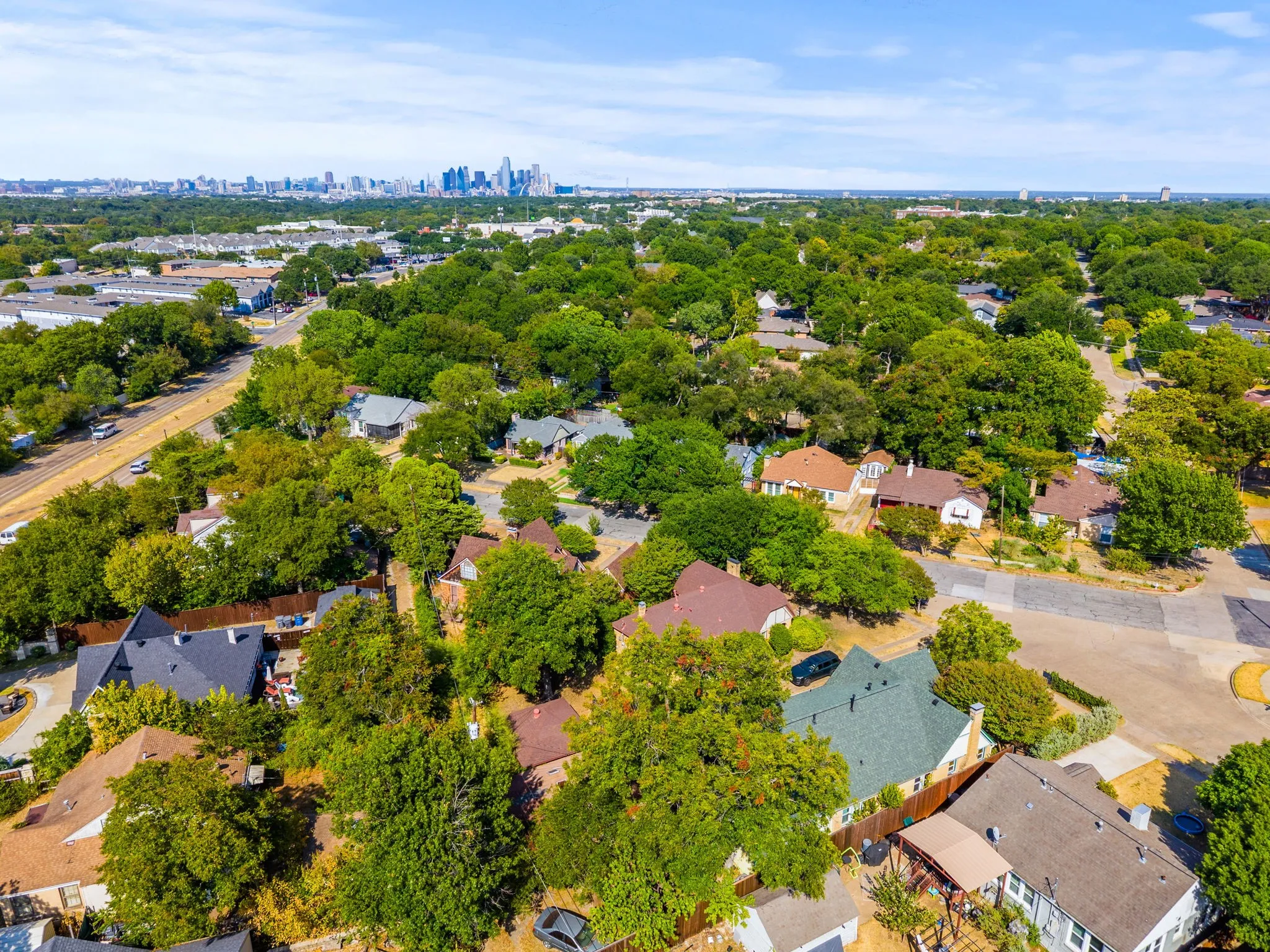 Residential neighborhood featuring mature trees and a distant city skyline