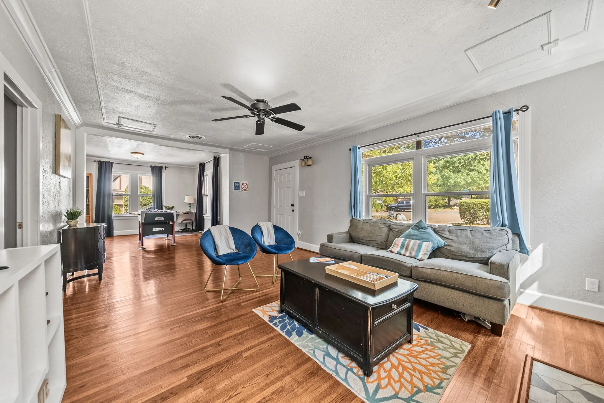 Hardwood flooring, crown molding, ceiling fan, and large windows
