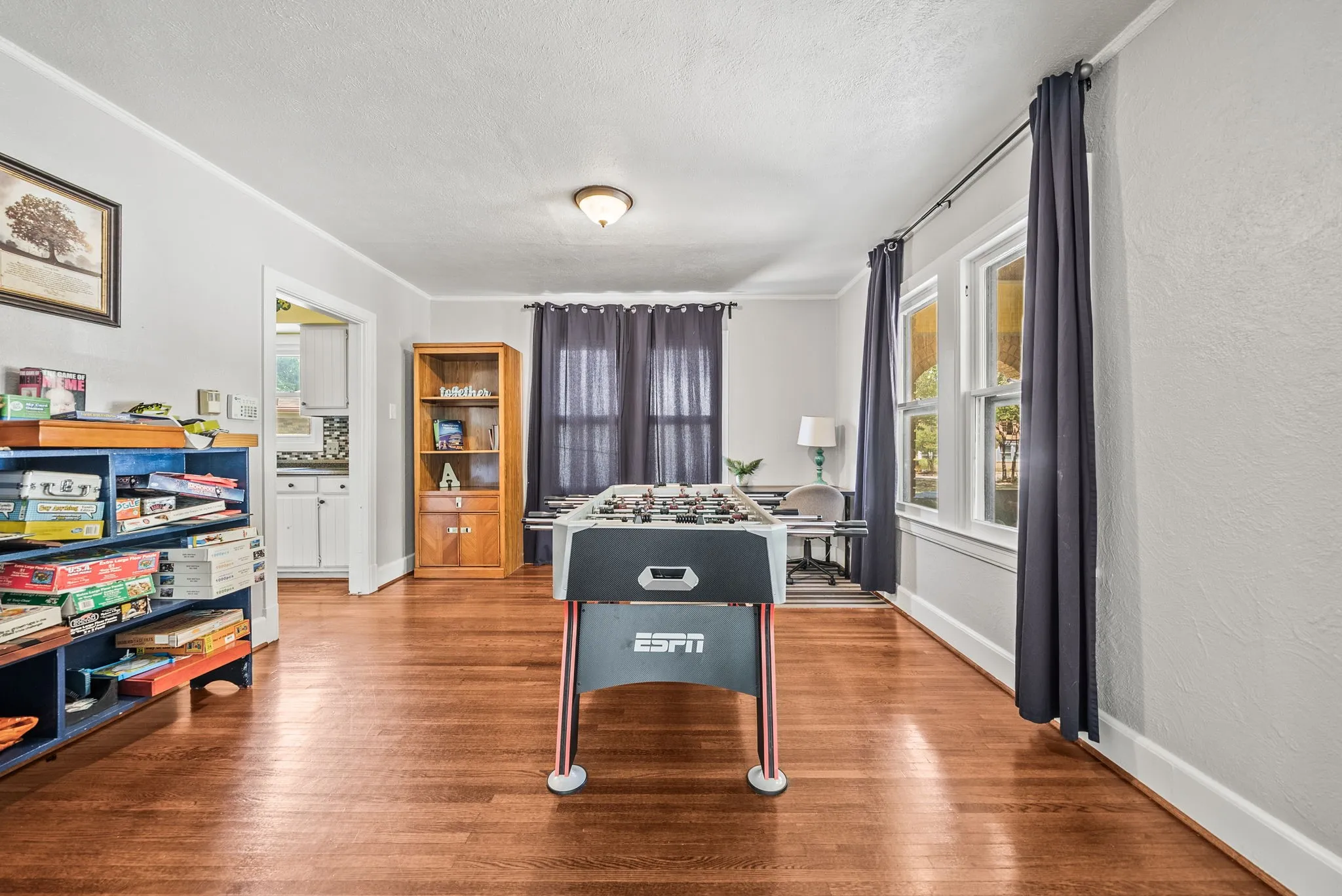 Hardwood flooring throughout, multiple windows with natural light, recessed lighting, and an open doorway leading to an additional room