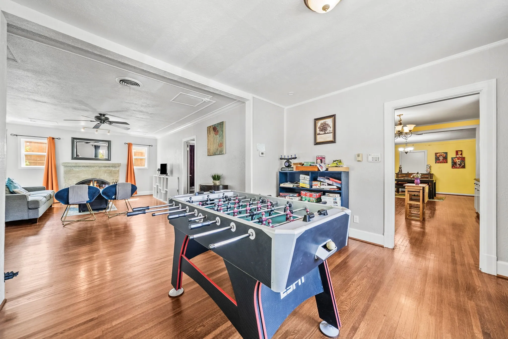 Hardwood flooring throughout, recessed archway, fireplace with stone surround, ceiling fan light fixture, and built-in shelving