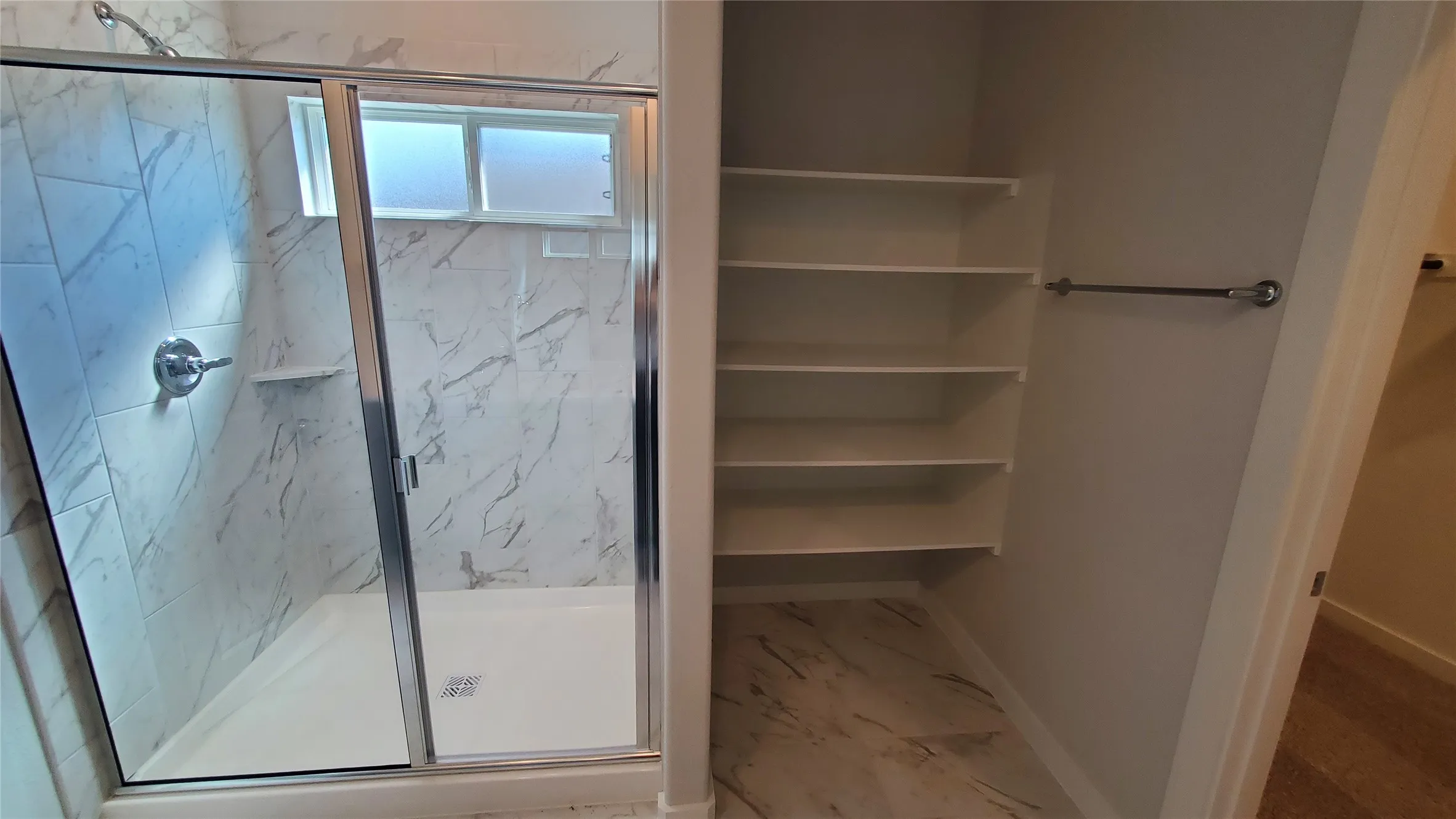 Shower with glass enclosure, chrome fixtures, and white tile surround