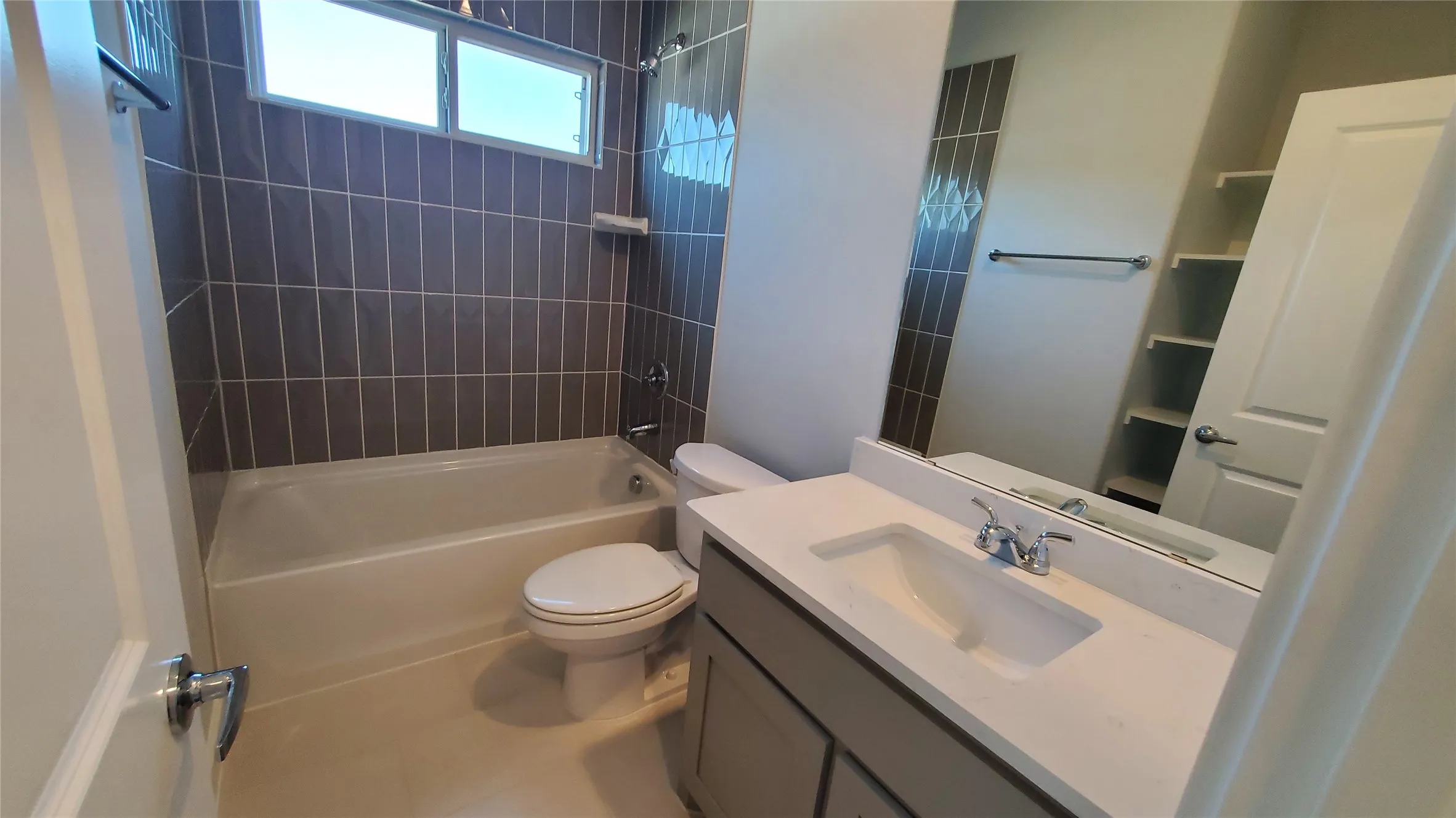 Bathroom featuring a built-in tub with tile surround, a single vanity with an integrated sink, and an expansive wall mirror