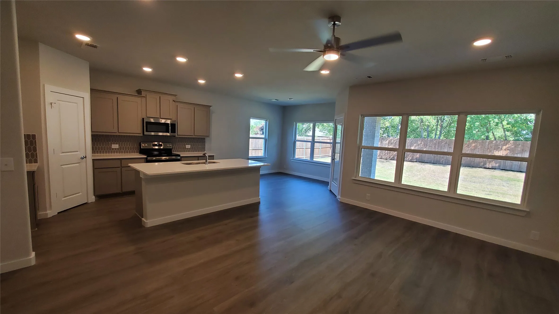 Open-concept living area with wood-finish flooring, recessed lighting, and a ceiling fan