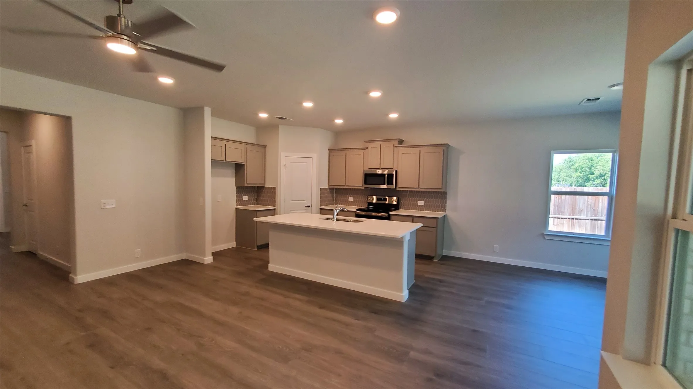 Open-concept living area featuring wood-finish flooring, recessed lighting, and a ceiling fan