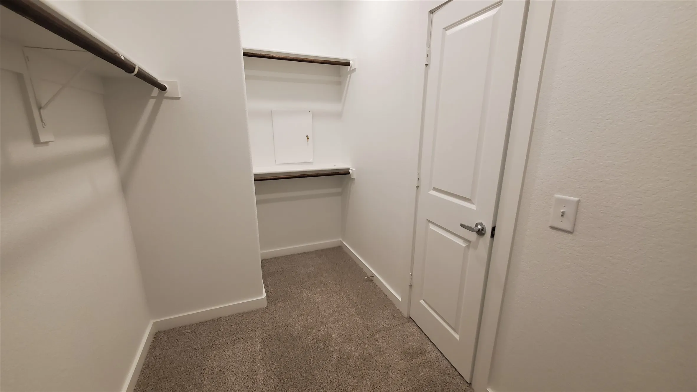 Walk-in closet featuring carpeted flooring, built-in shelving, and hanging rods