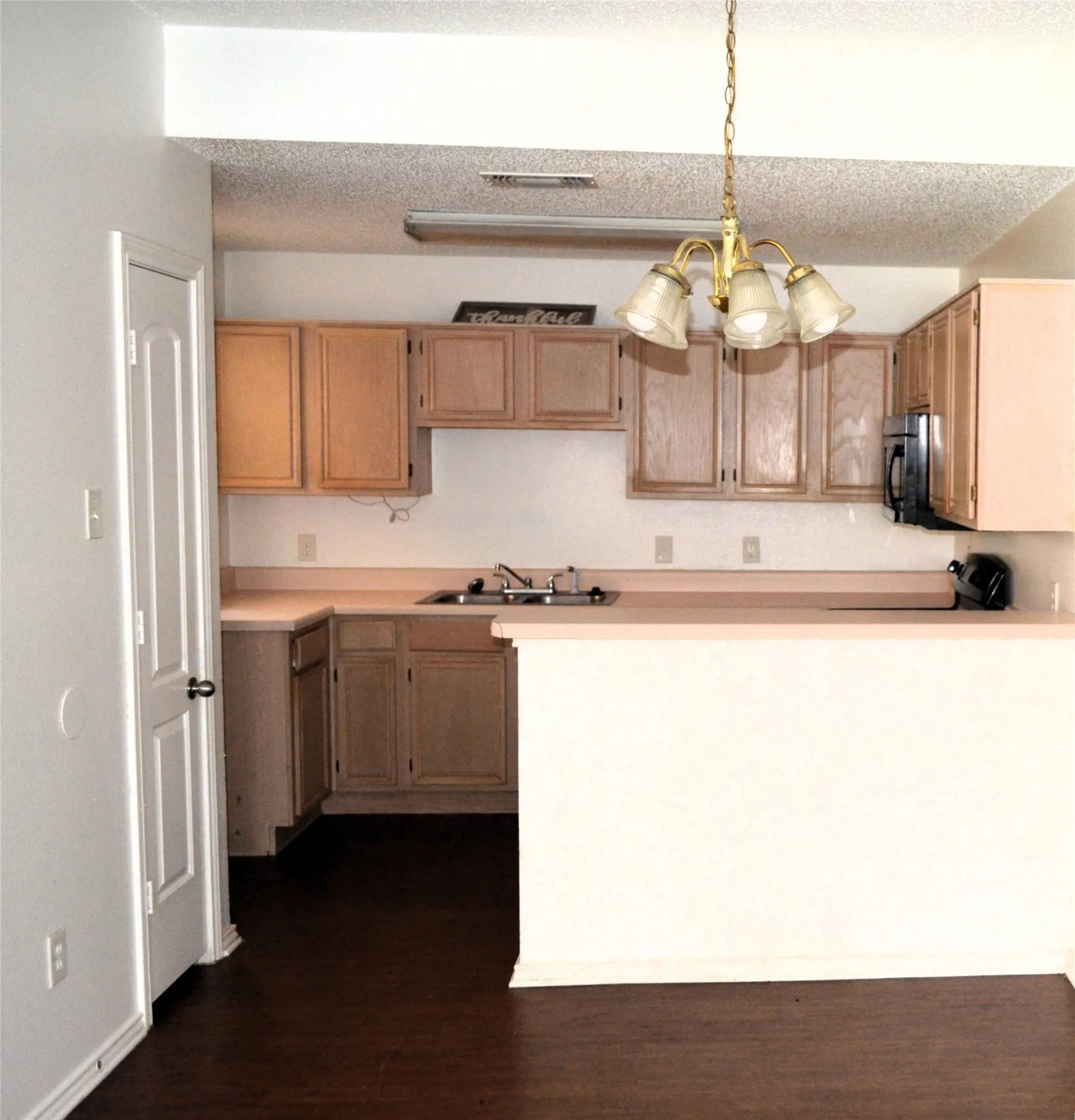 Kitchen featuring wood-finish cabinetry, a built-in microwave, a double basin sink, and a breakfast bar