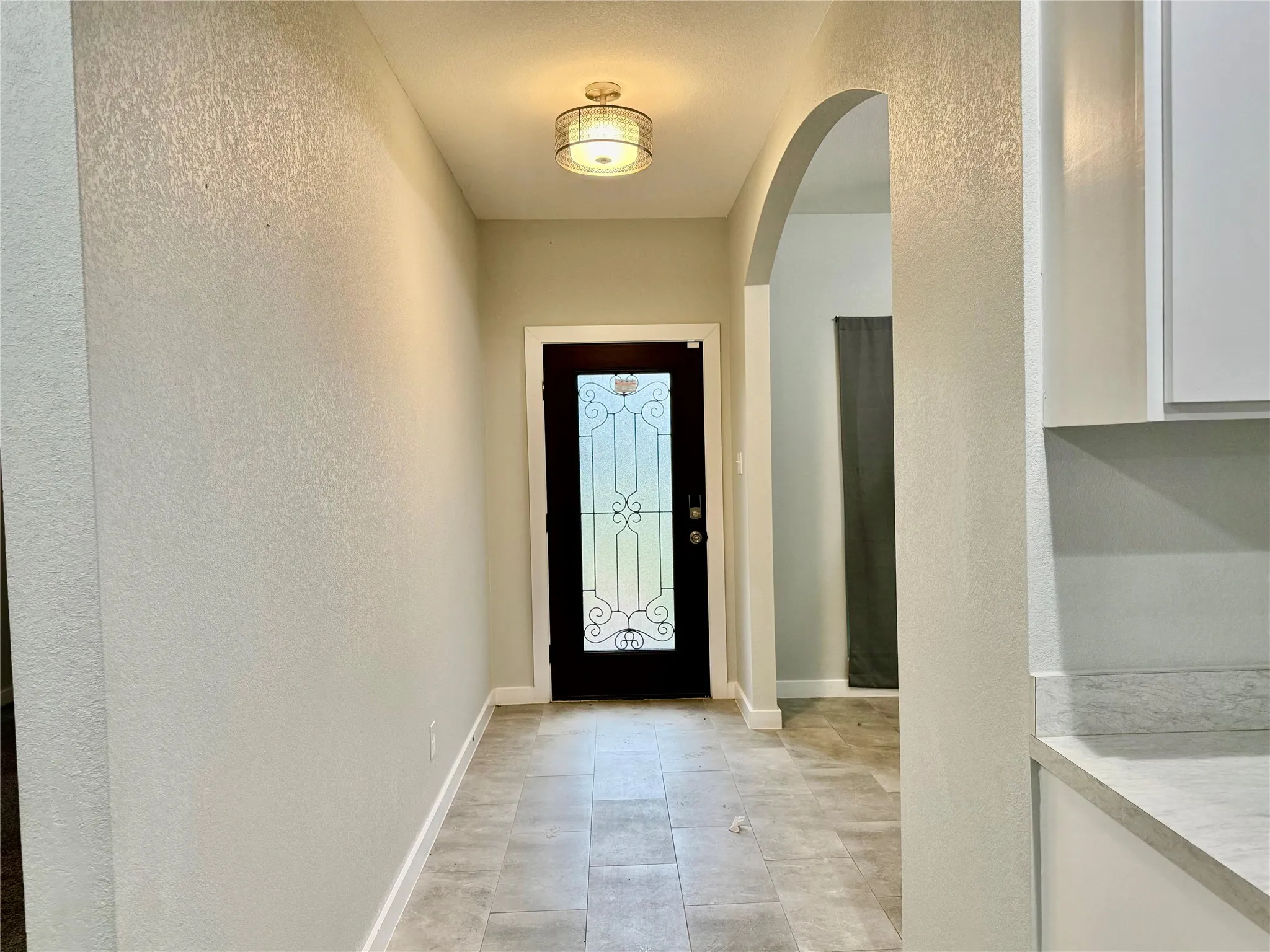 Entryway with tiled flooring, an arched doorway, and a decorative glass-paneled entry door