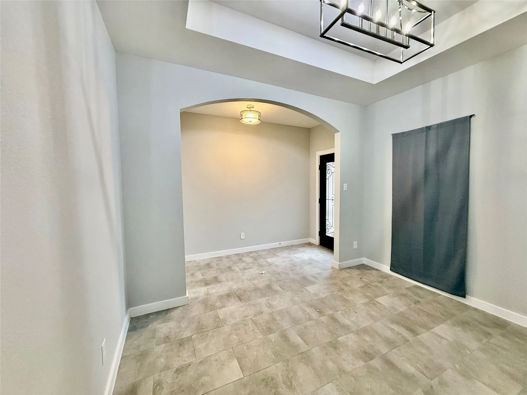 Recessed ceiling, tray ceiling, tile flooring, arched doorway, and decorative front door with glass inserts