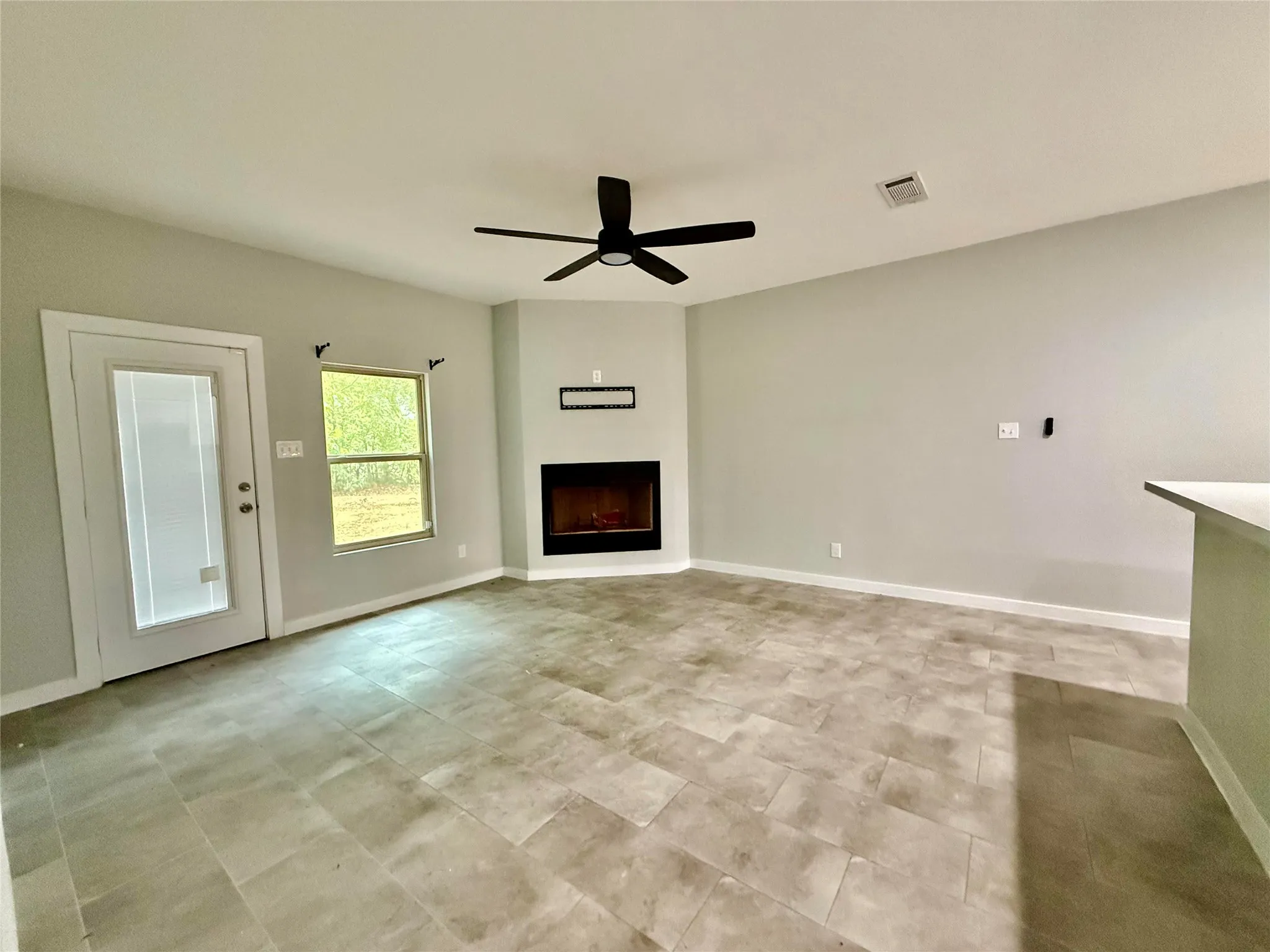 Tiled flooring, corner fireplace, ceiling fan, and white trim accents