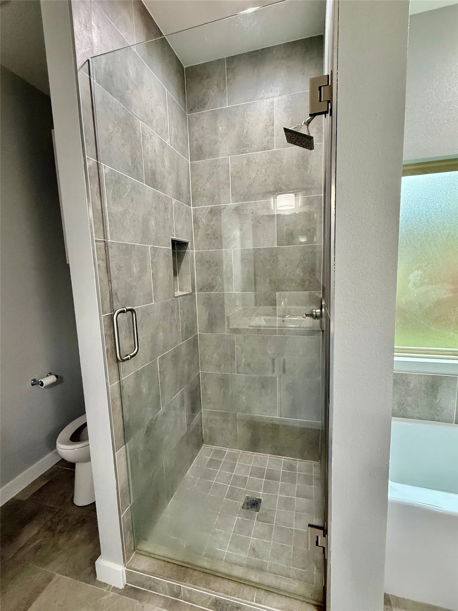 Walk-in shower with clear glass enclosure and built-in shelving