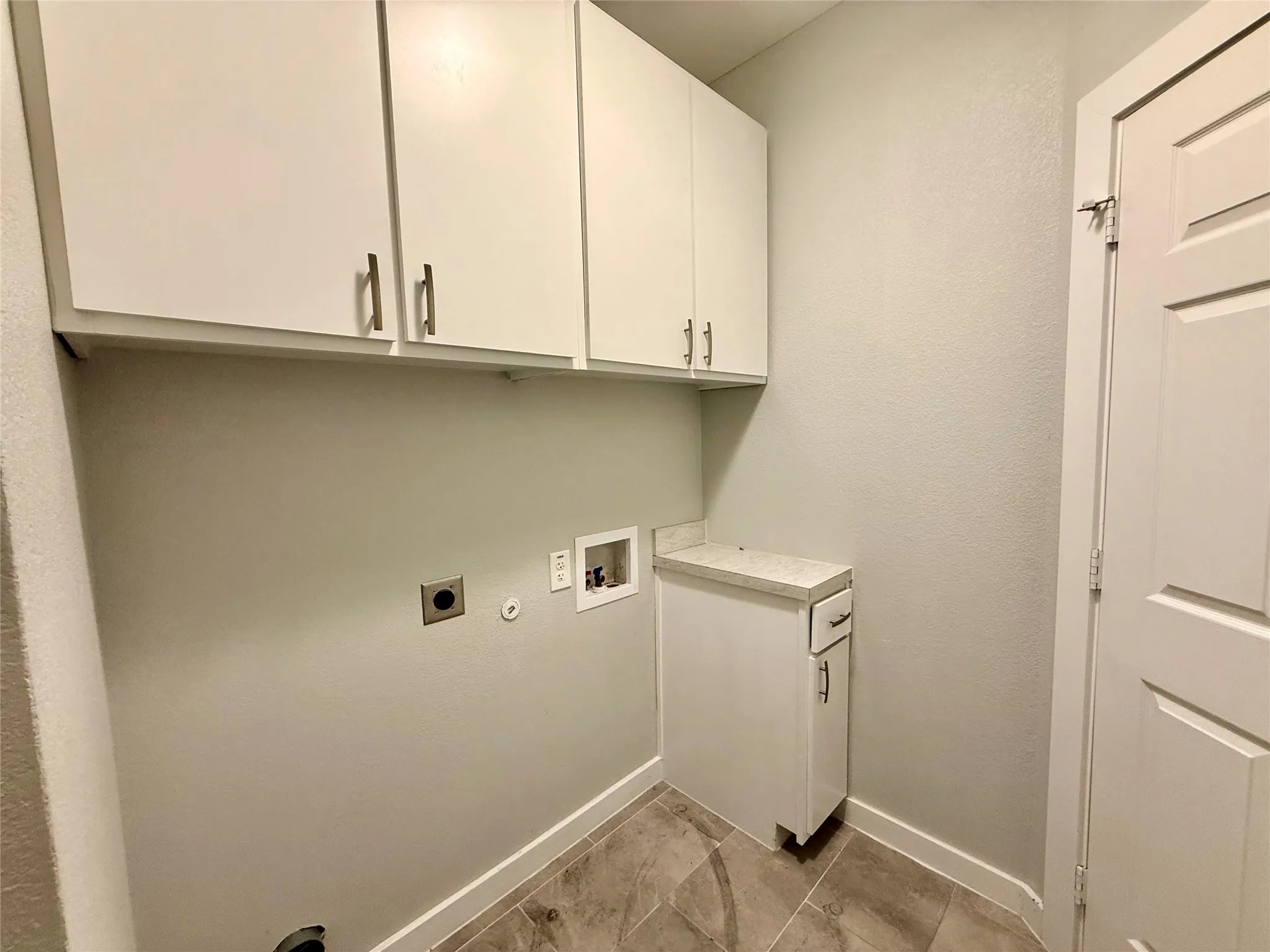 White shaker-style cabinetry with brushed nickel hardware, stone-finish countertop, and tile flooring
