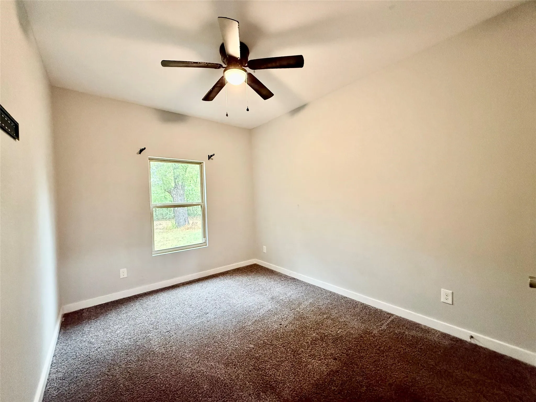Vaulted ceiling with a ceiling fan, neutral wall paint, carpet flooring, and a single window