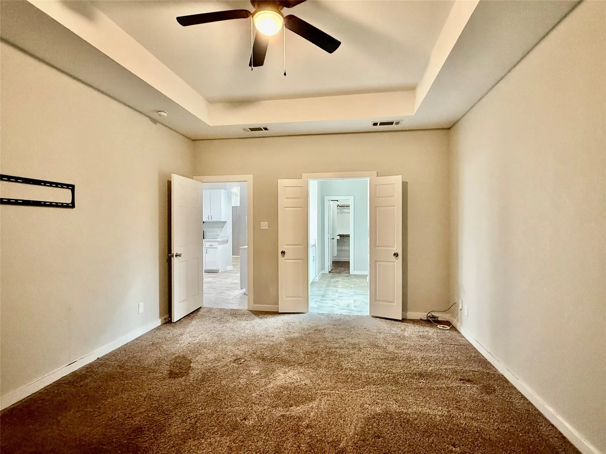 Recessed ceiling with a ceiling fan, light-toned walls, and brown carpeting