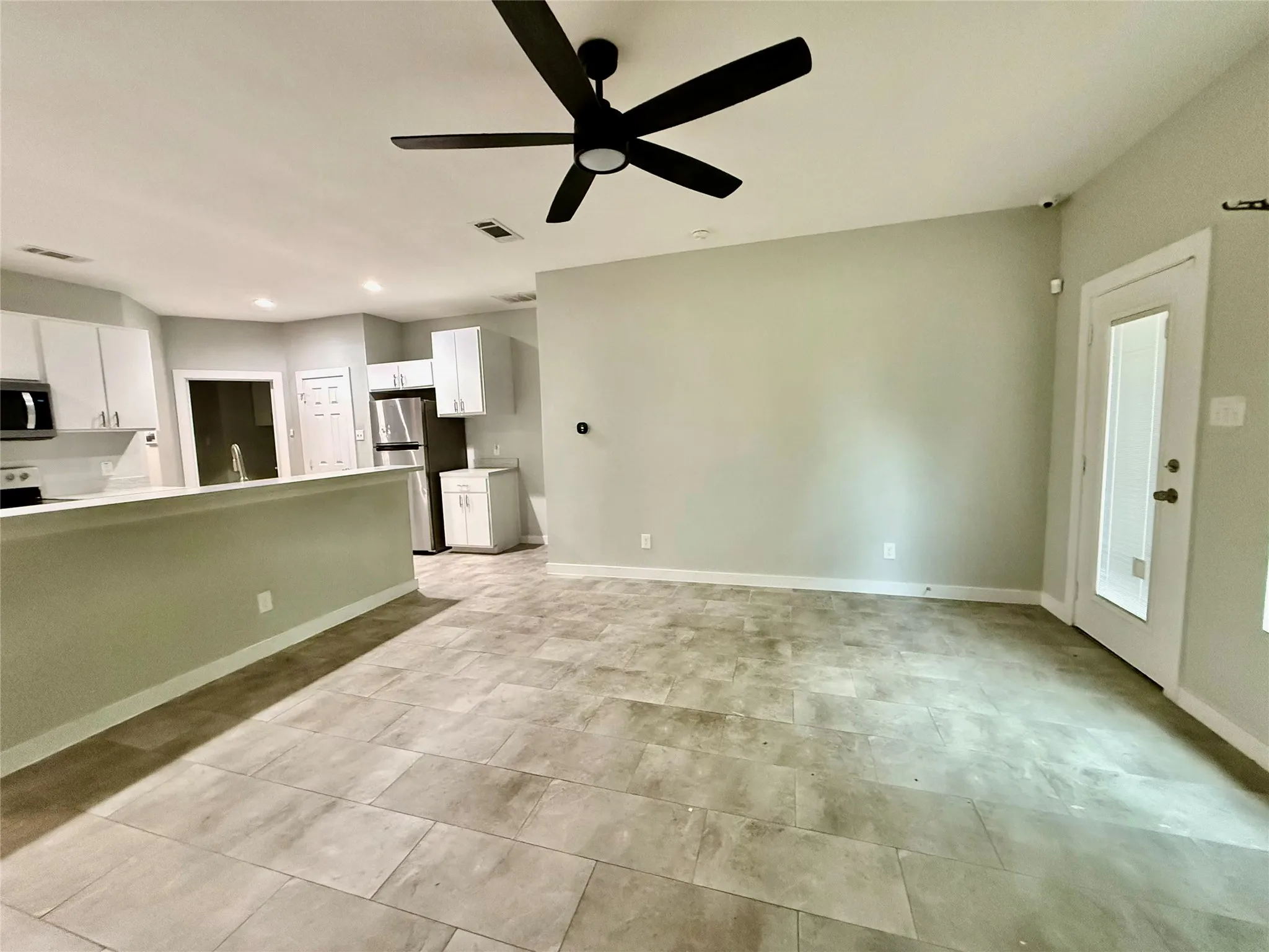 Tile flooring throughout, white cabinetry, stainless steel appliances, and ceiling fan