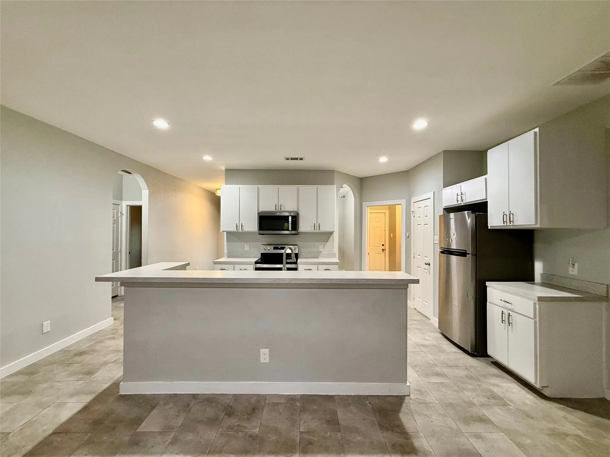 Kitchen featuring light gray cabinetry, stainless steel appliances, a breakfast bar, and tile flooring