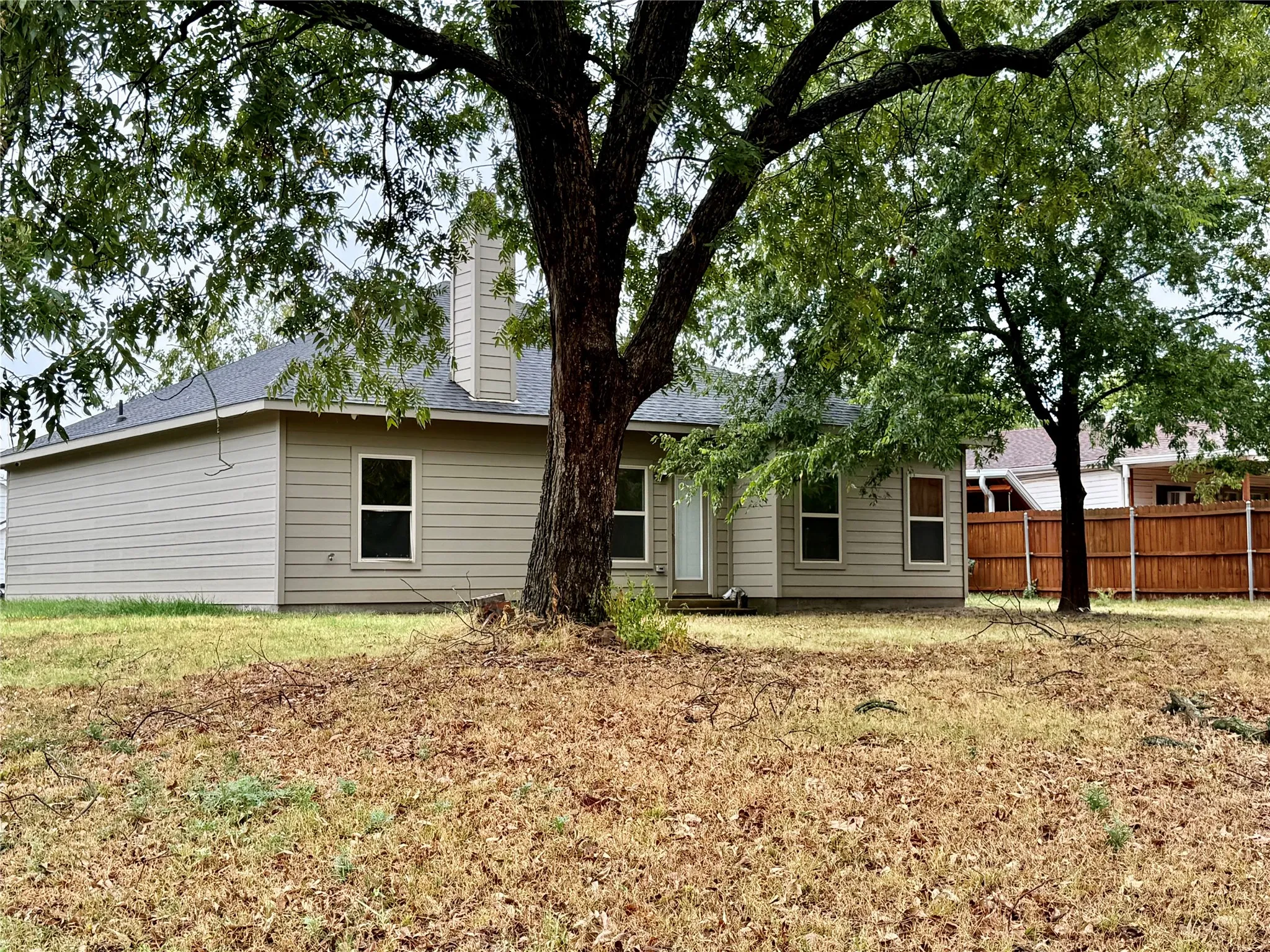 Exterior featuring neutral-toned siding, a dark shingle roof, a prominent chimney, and multiple windows