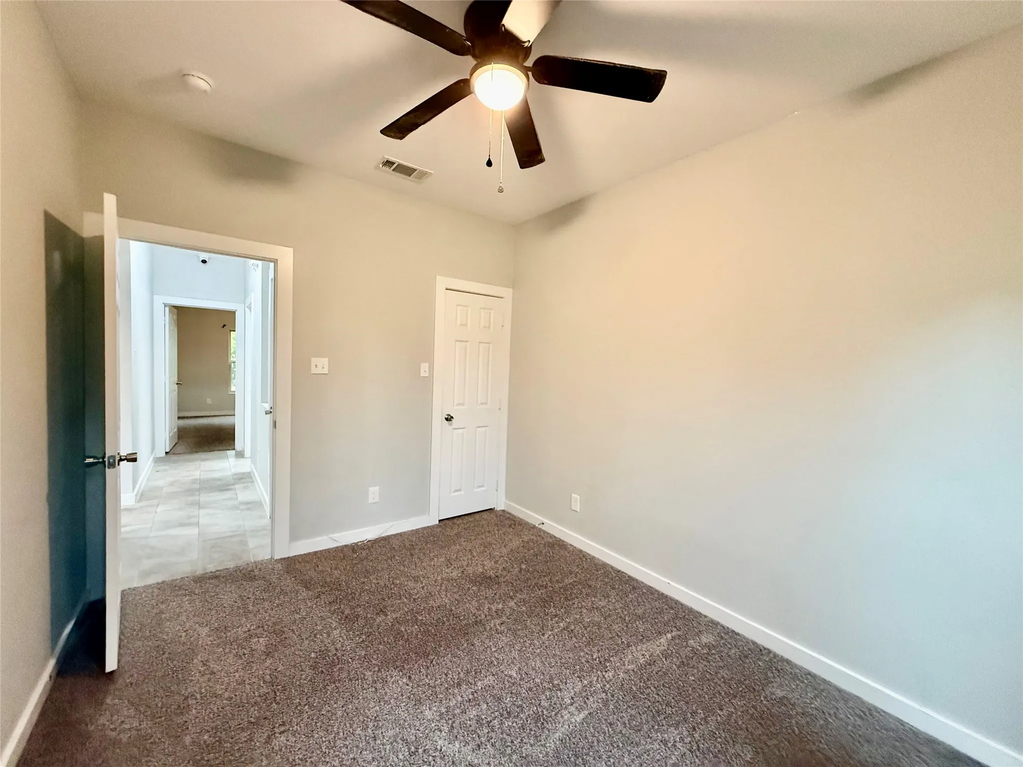 Ceiling fan with integrated lighting, neutral wall paint, carpet flooring, and white paneled door