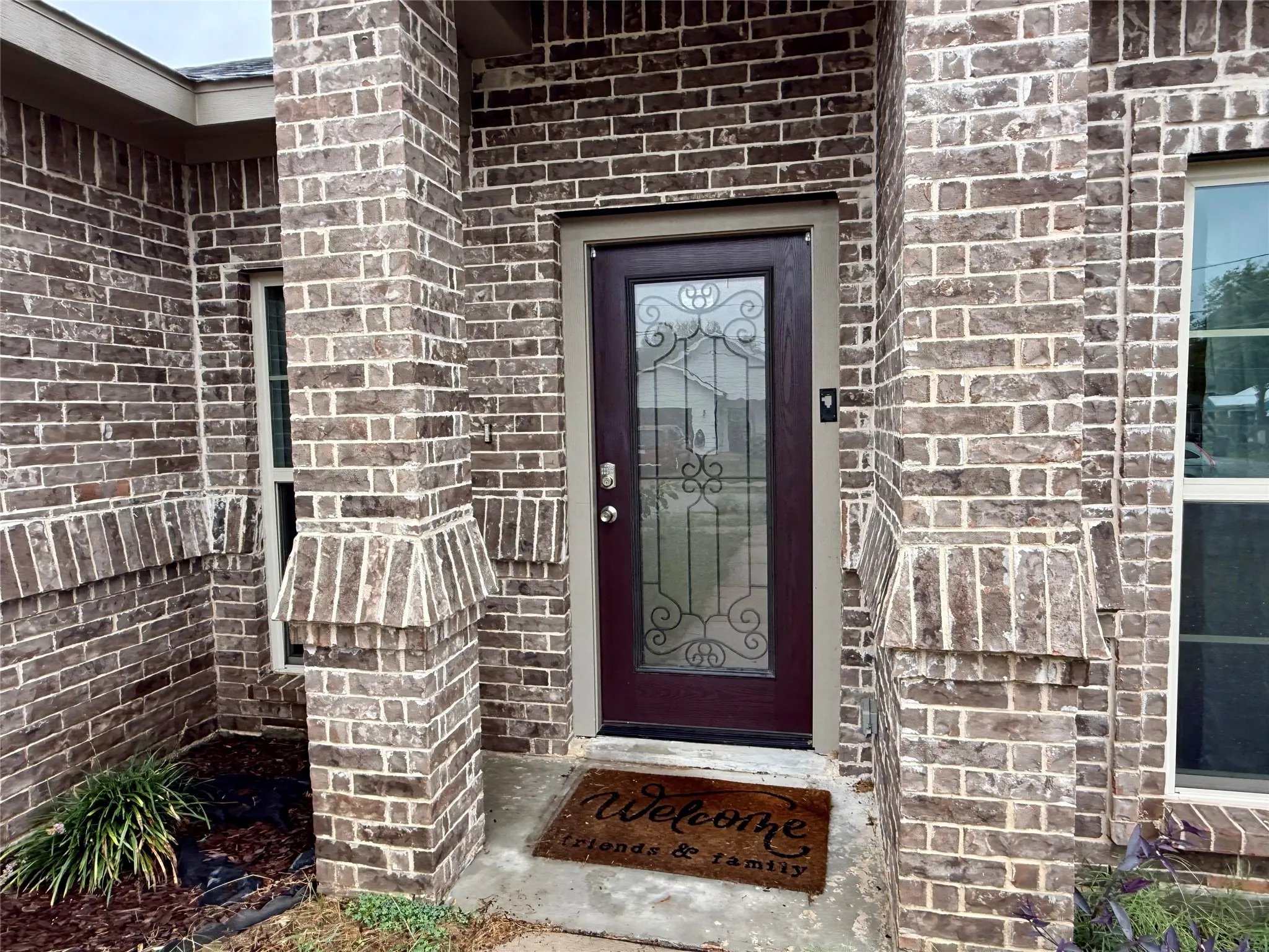Brick exterior with decorative columns, transom window, and a glass-paneled entry door