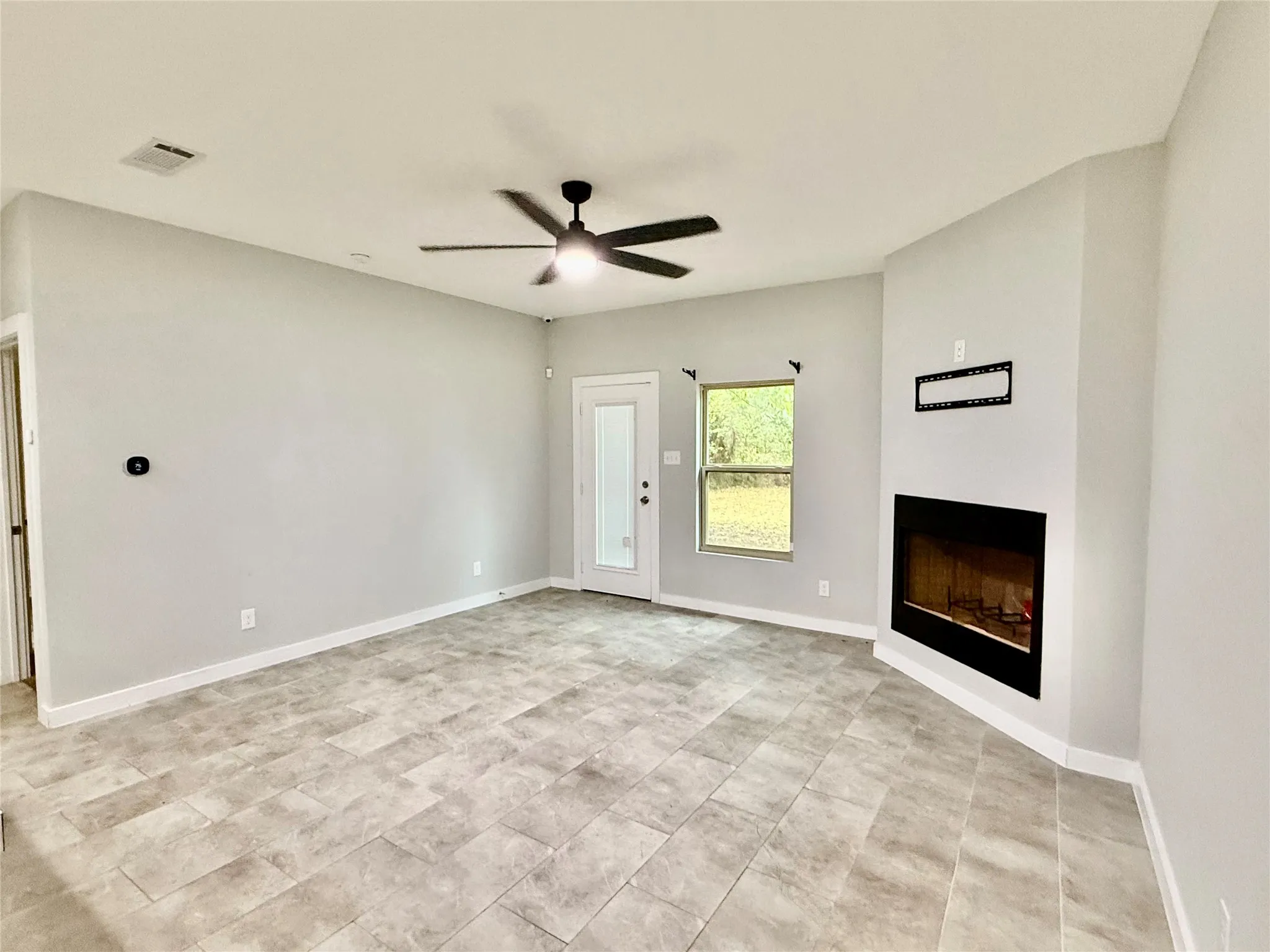 Fireplace with mantel, tile flooring, ceiling fan with integrated lighting, recessed lighting, and a glass-paneled exterior door
