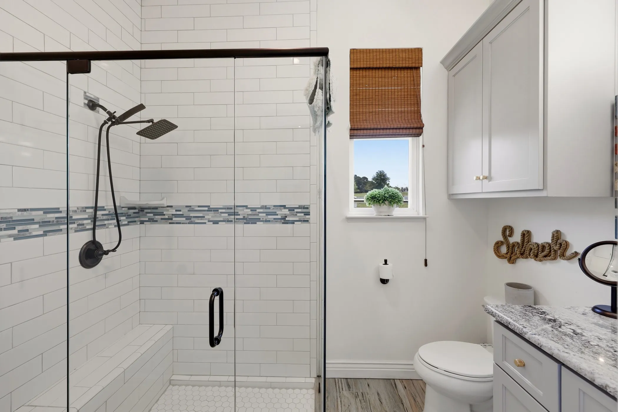 Glass-enclosed shower with subway tile surround, integrated bench, and dual showerheads