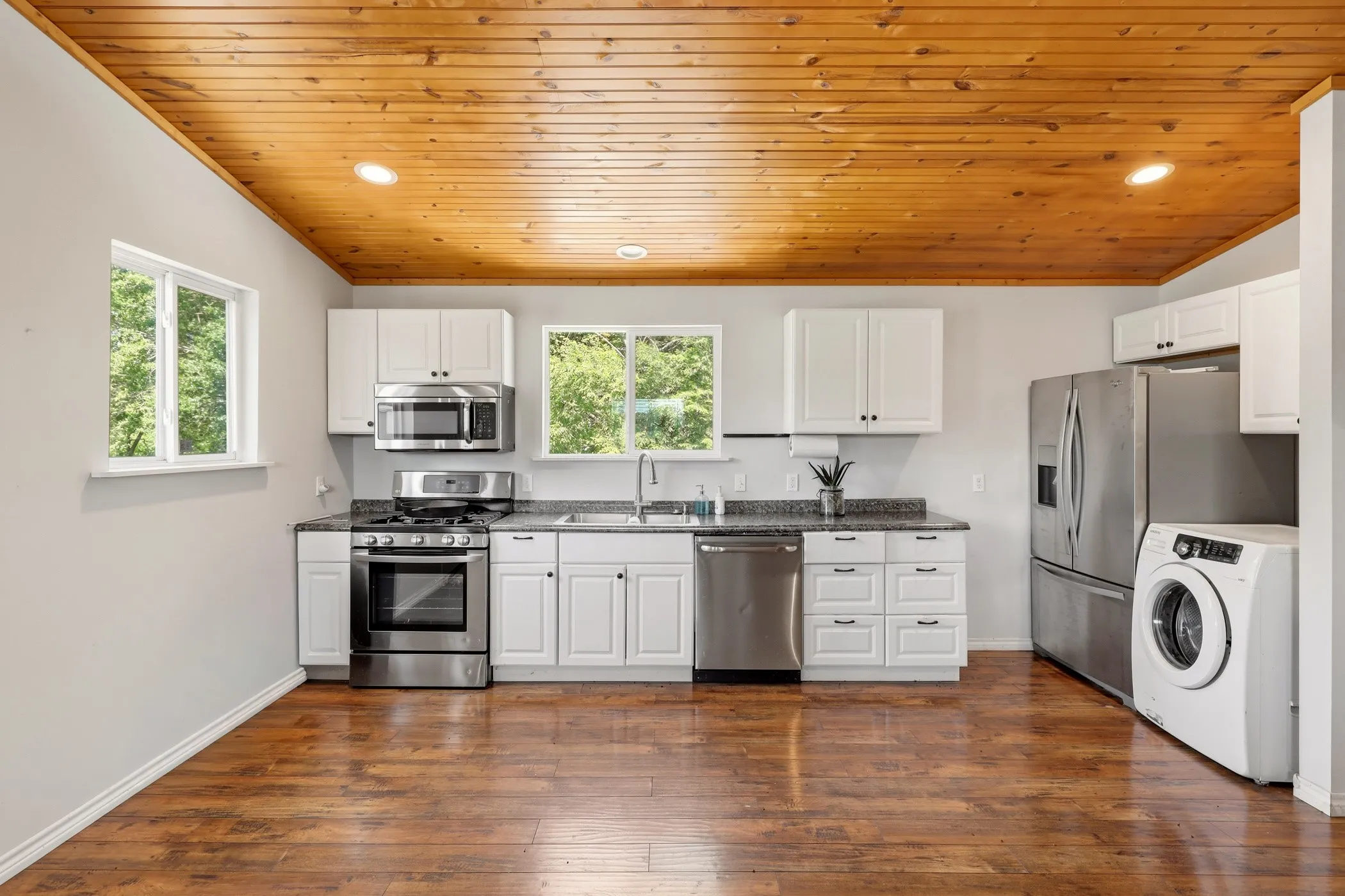 Kitchen featuring extensive white cabinetry, stainless steel appliances, wood-finish flooring, a wood-paneled ceiling, and recessed lighting