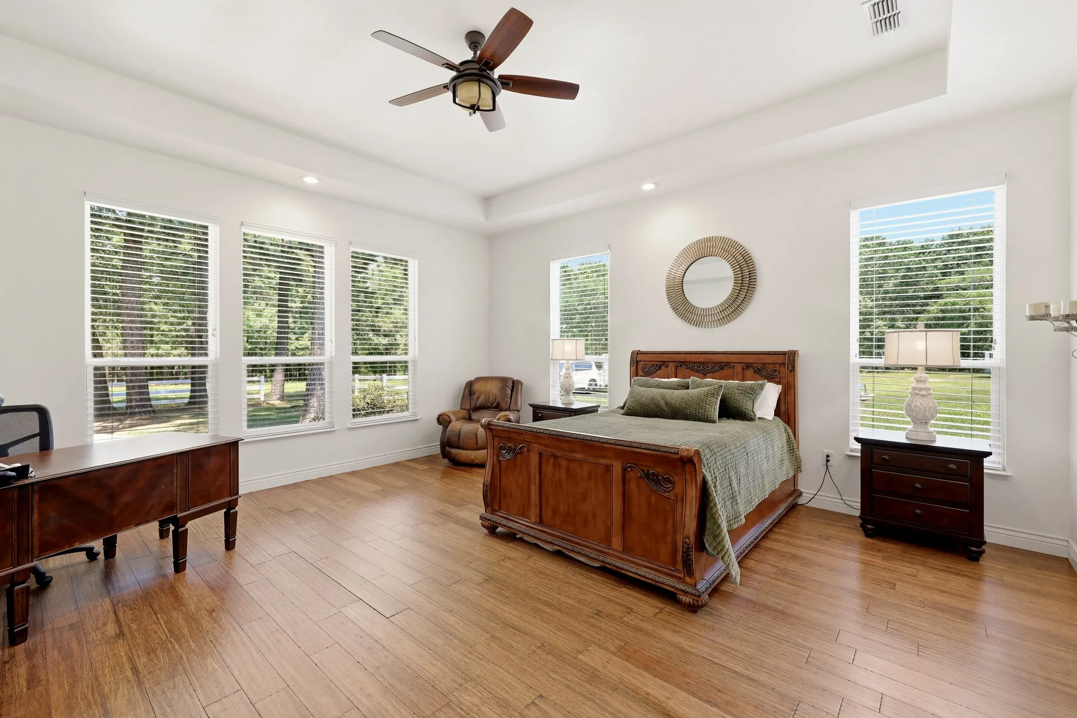 Spacious primary bedroom featuring wood-finish flooring, a coffered ceiling with recessed lighting, and a ceiling fan with integrated light fixture