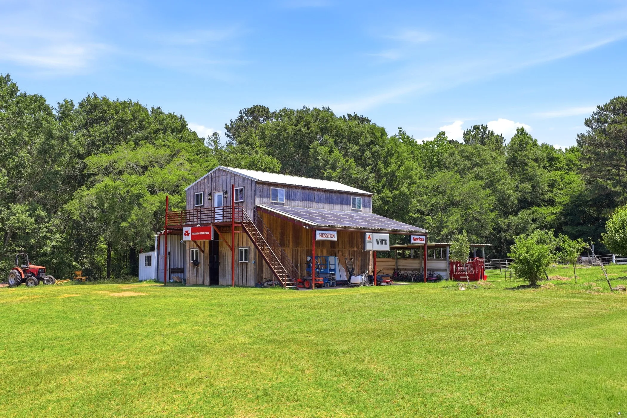 Two-story wood-sided structure featuring an upper-level balcony, exterior staircase, covered porch, and a metal roof