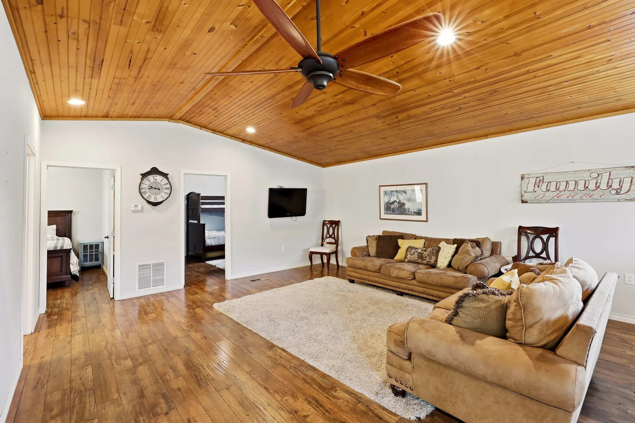 Wood-finish flooring throughout, featuring a natural wood-plank ceiling with recessed lighting and a ceiling fan
