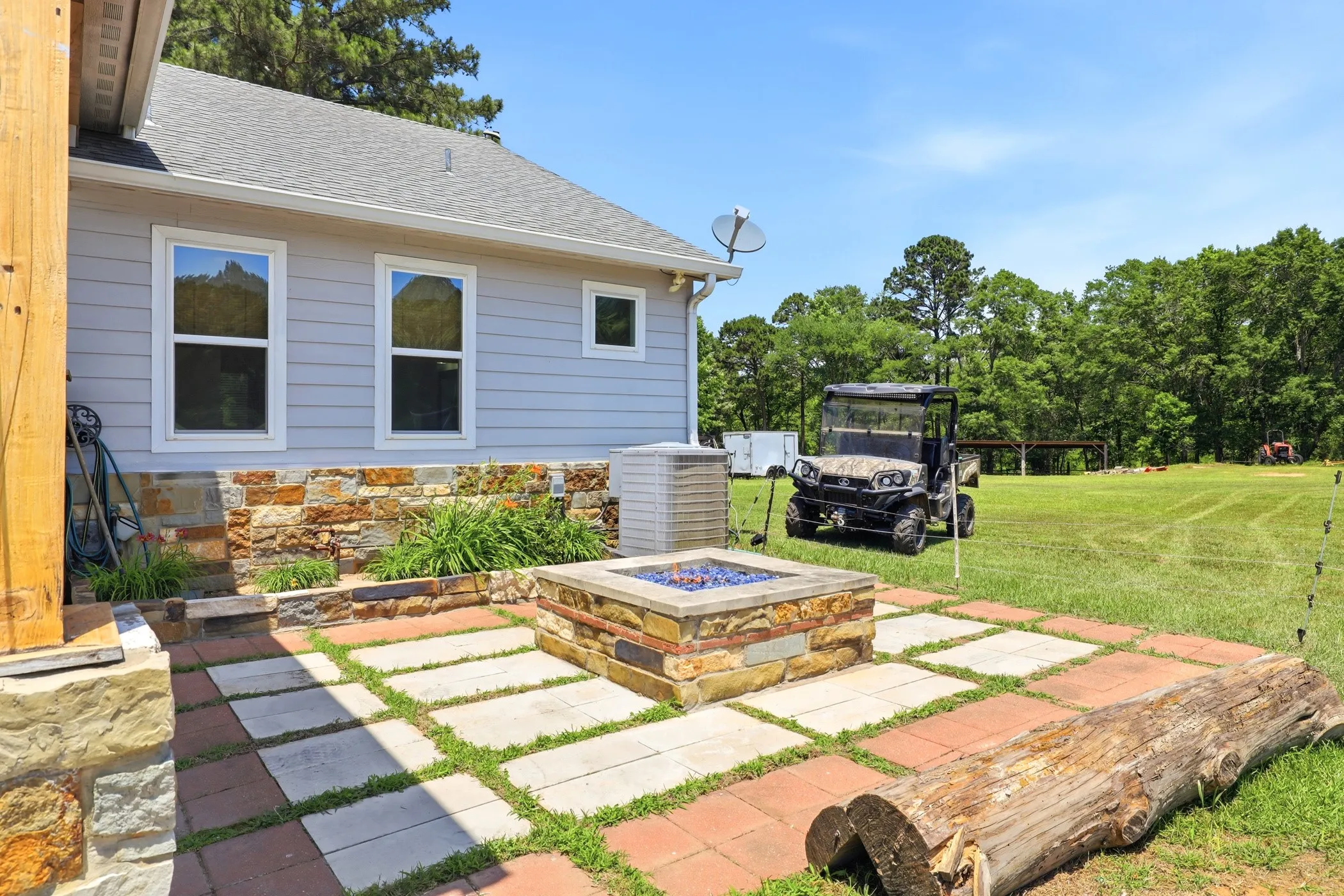 Outdoor patio featuring a built-in stone fire pit, paver and brick hardscaping, and a stone-clad foundation