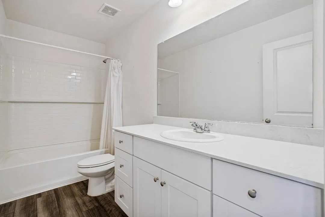 Bathroom featuring a white vanity with an integrated sink, polished chrome faucet, and expansive wall-mounted mirror