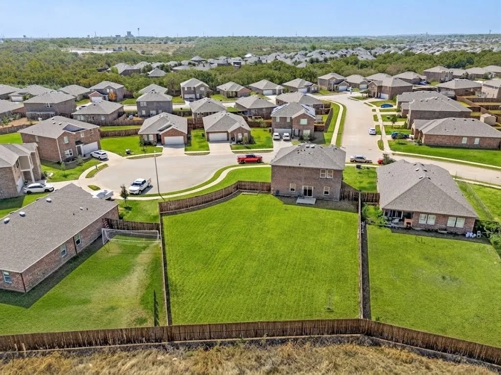 Expansive lot with manicured lawn, established privacy fencing, and direct access to a paved street