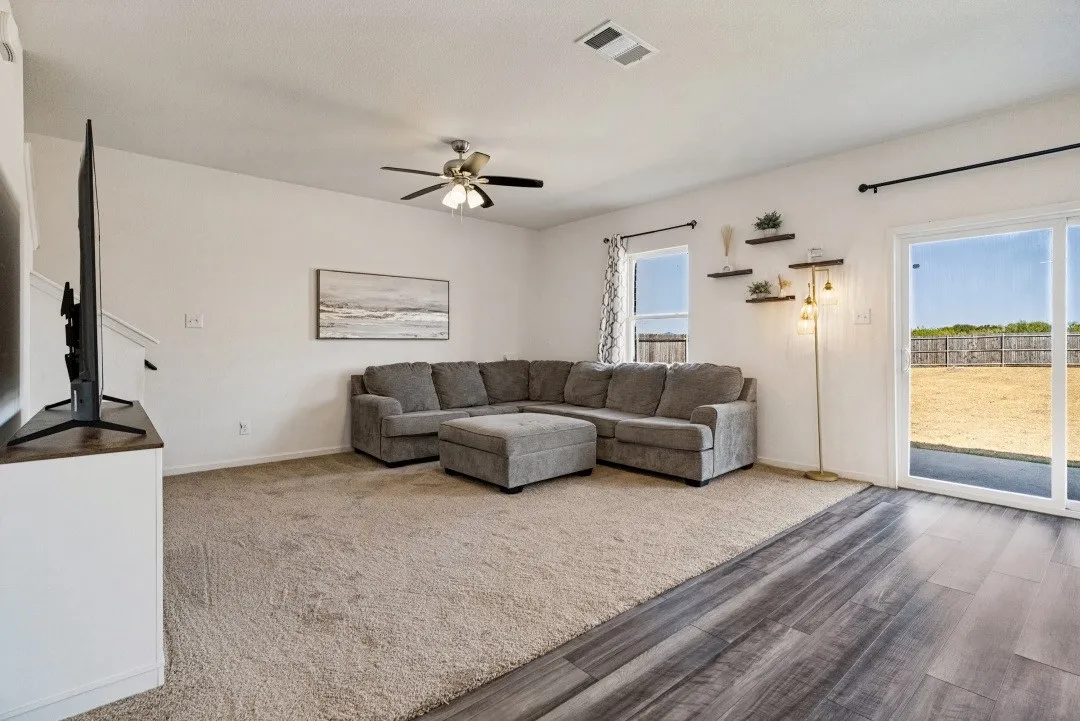 Sliding glass door to outdoor space, ceiling fan, wood-finish flooring, and light-toned carpet