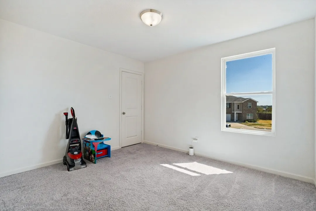 Light gray wall-to-wall carpeting, white painted walls, white trim, single window with white frame, and a flush mount ceiling light fixture