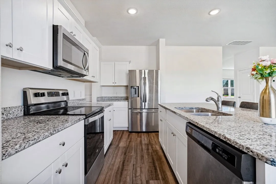 White cabinetry, granite countertops, stainless steel appliances, wood-finish flooring, and recessed lighting