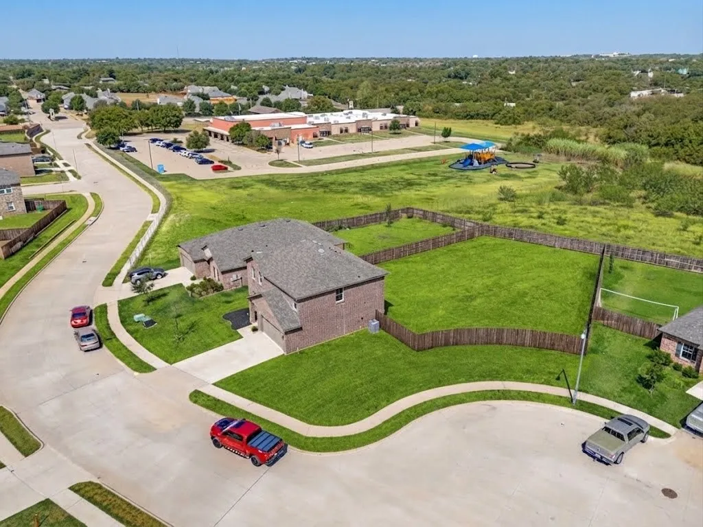 Brick exterior residence with an attached garage, featuring a fenced backyard with a manicured lawn