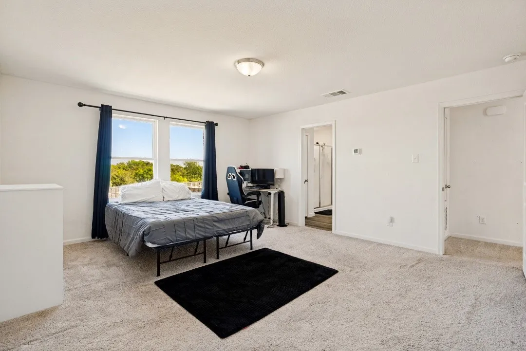 Expansive room featuring carpeted flooring, two large windows, a ceiling-mounted light fixture, and white wall finishes