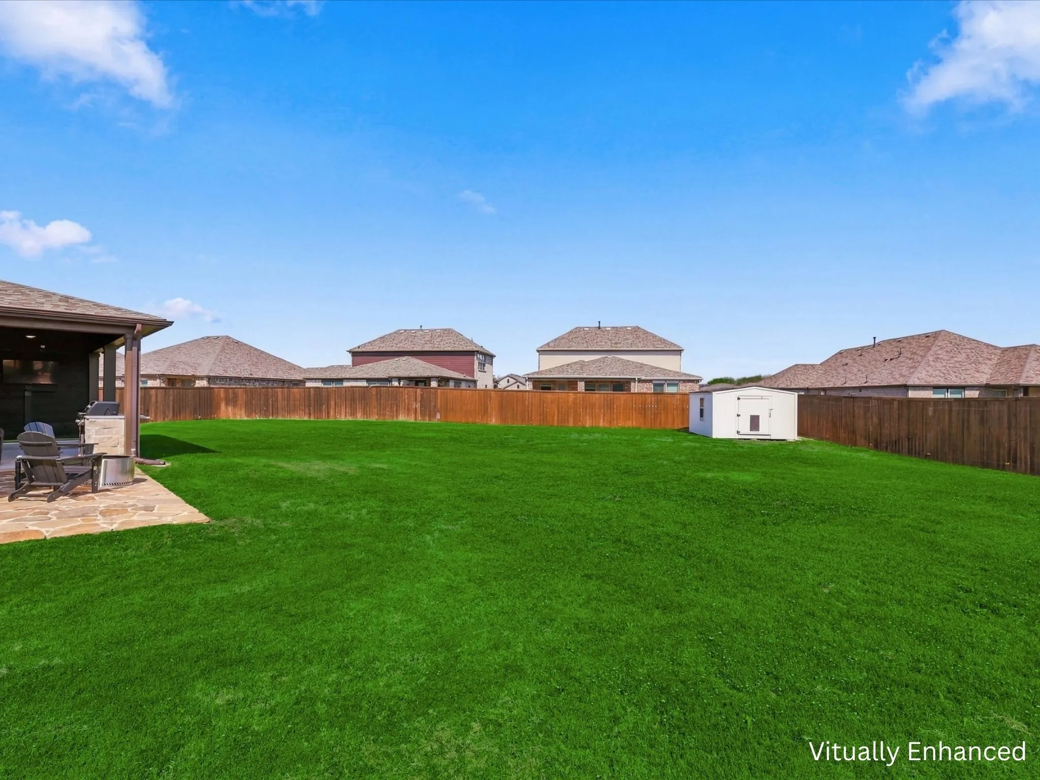 Oversized backyard showing back patio entertaining area and storage building.
