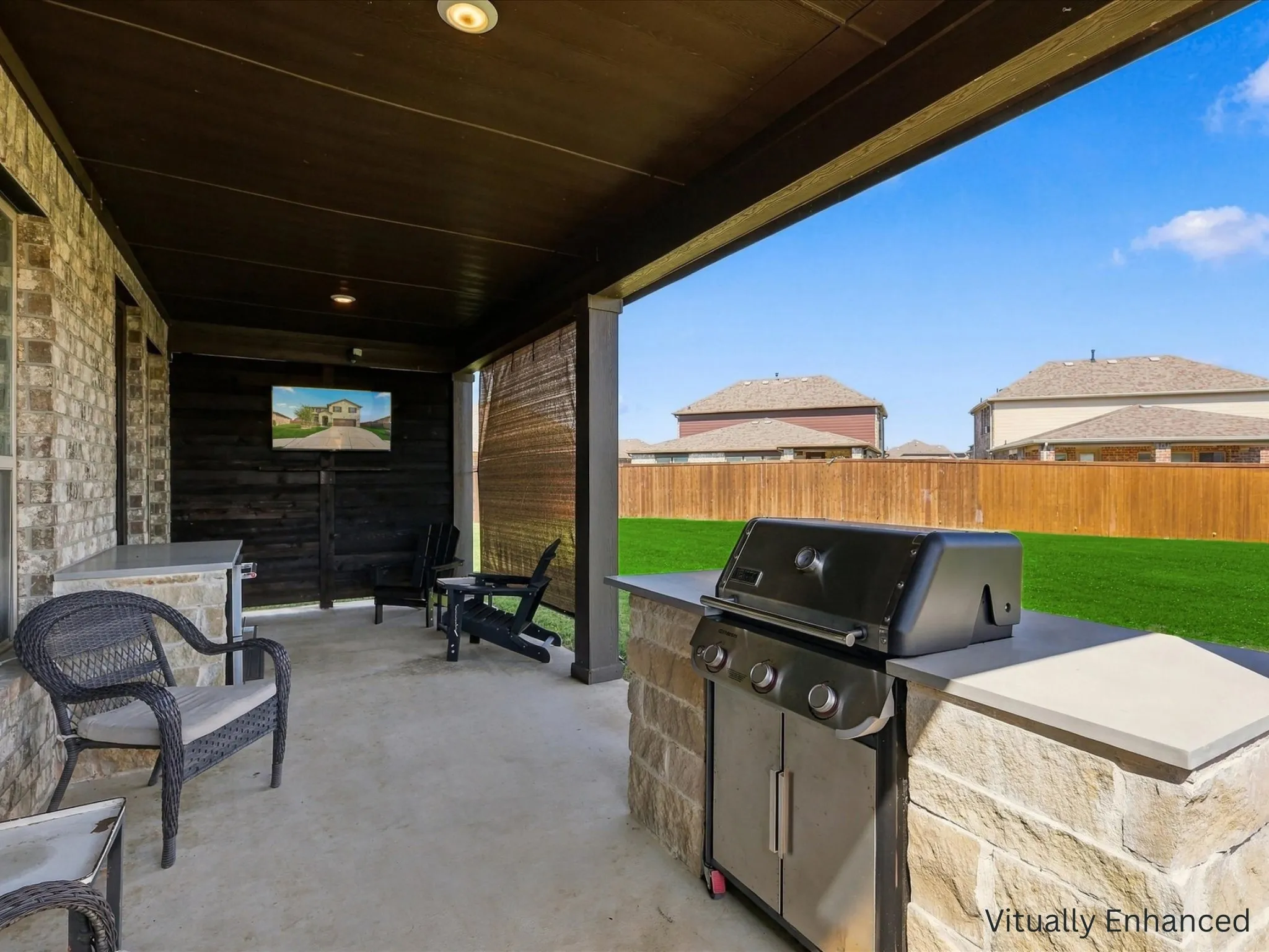 Back patio entertaining area with wall to attach TV and built in refrigerator and grill.