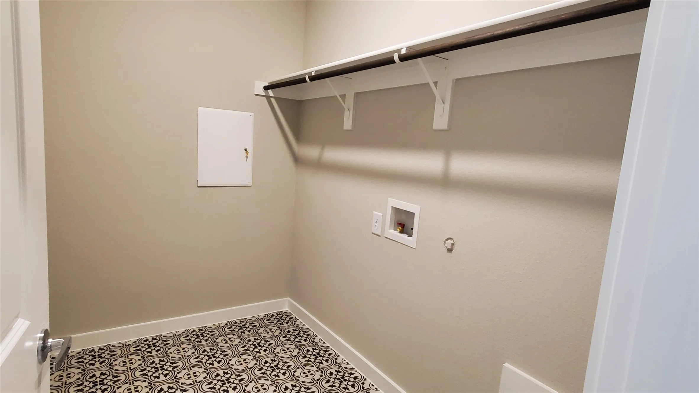 Built-in shelving with hanging rod, patterned floor tile, and light neutral wall paint