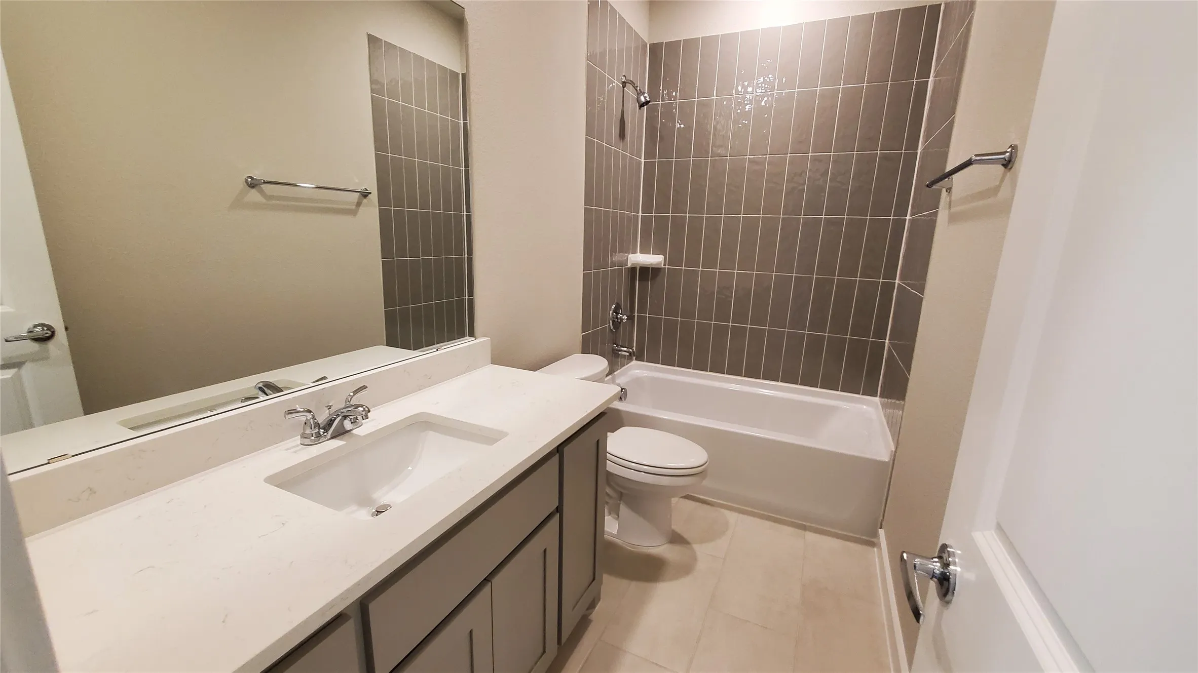 Bathroom featuring a single vanity with an integrated sink, polished chrome faucet, and a large wall mirror