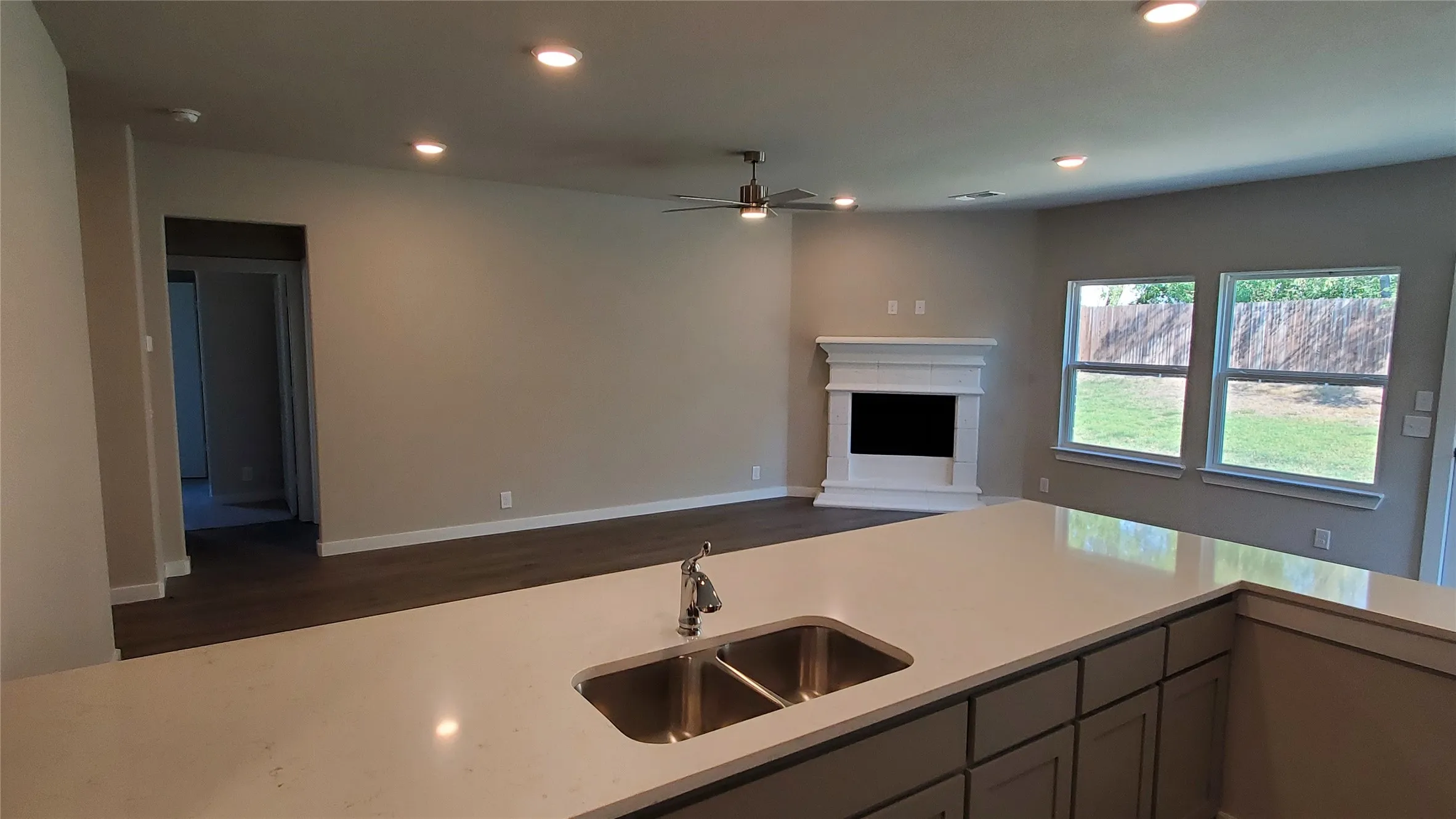 Kitchen island with a double basin stainless steel sink, light-colored countertops, and recessed lighting