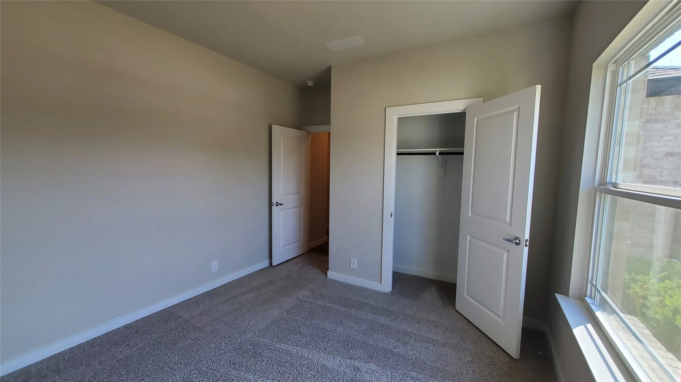 Carpeted room featuring a white interior door, a bi-fold closet with hanging rod, and a double-paned window