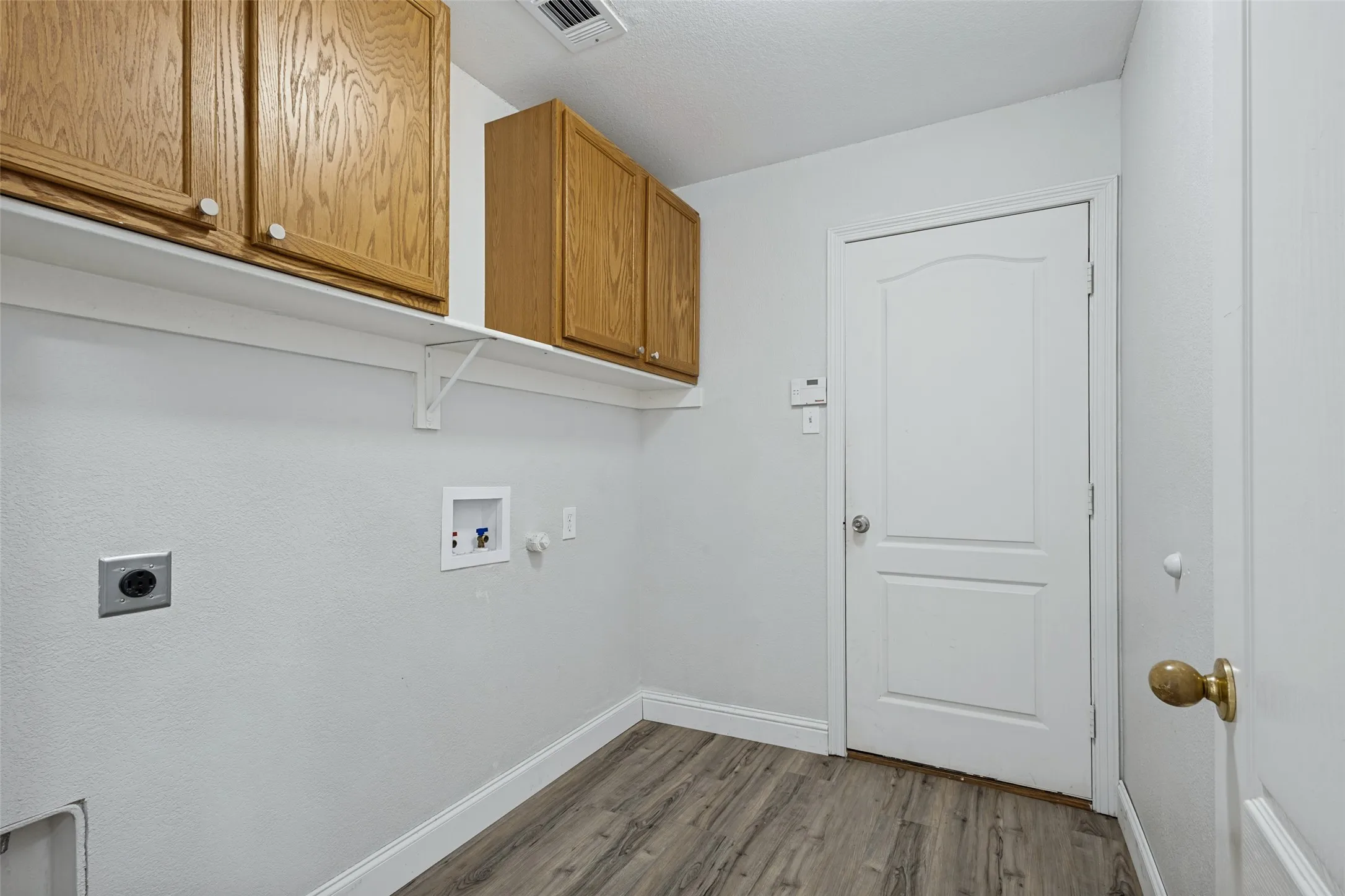 Overhead cabinets, area for full sized W/D leading into the 2 car garage
