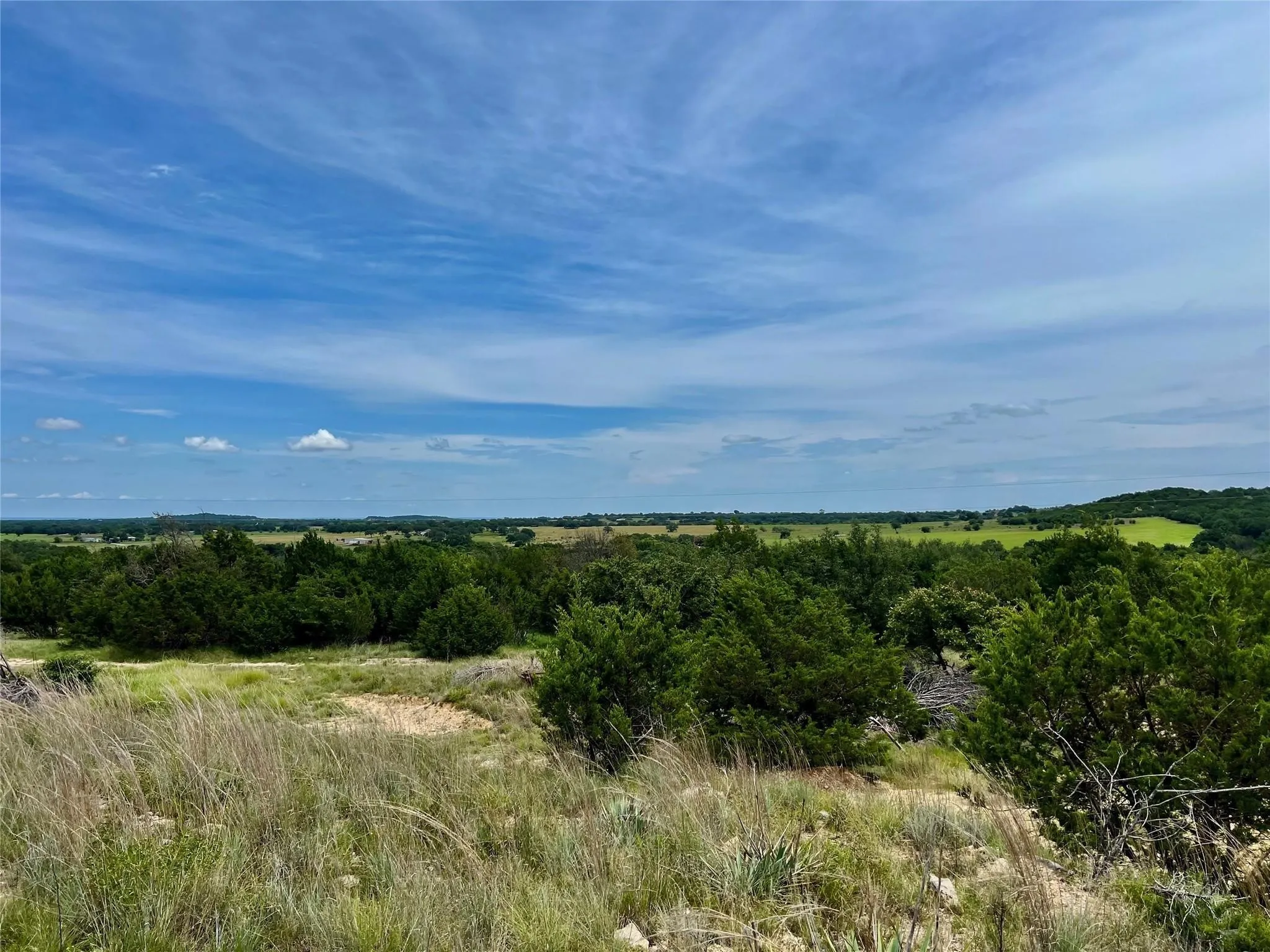 Expansive natural landscape featuring varied terrain, abundant green foliage, and a broad horizon
