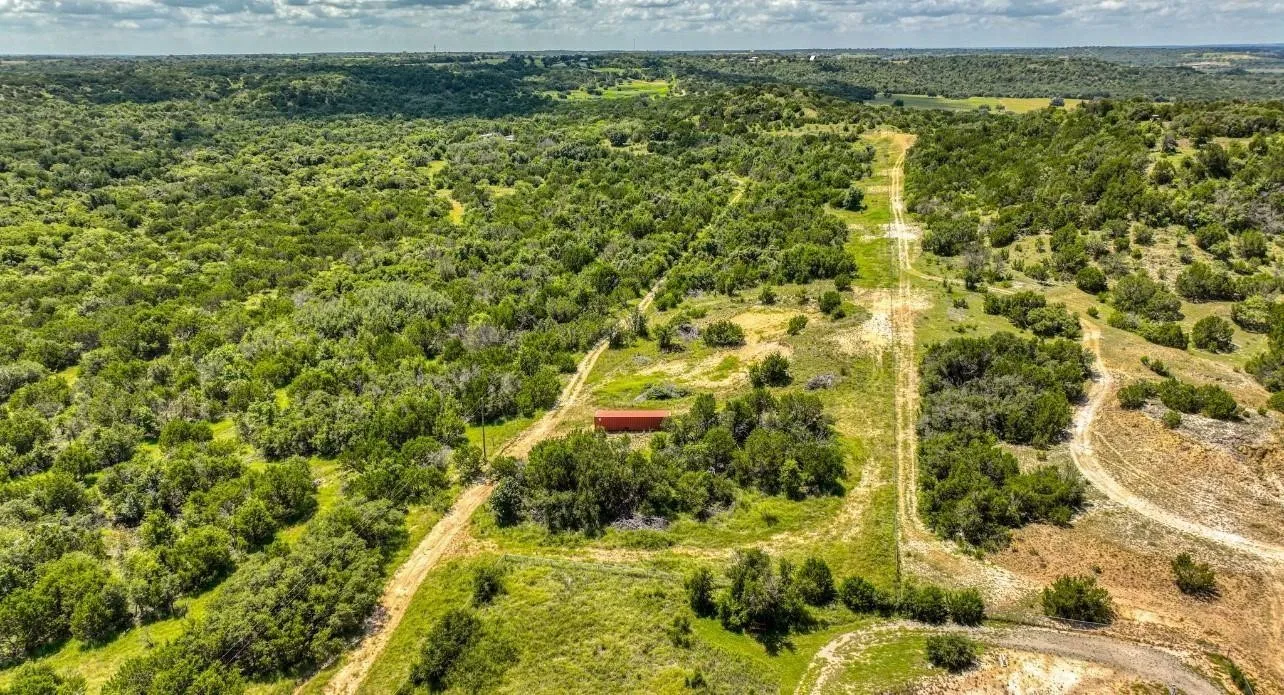 Expansive natural landscape with varied terrain, dense tree coverage, and a cleared path through the property
