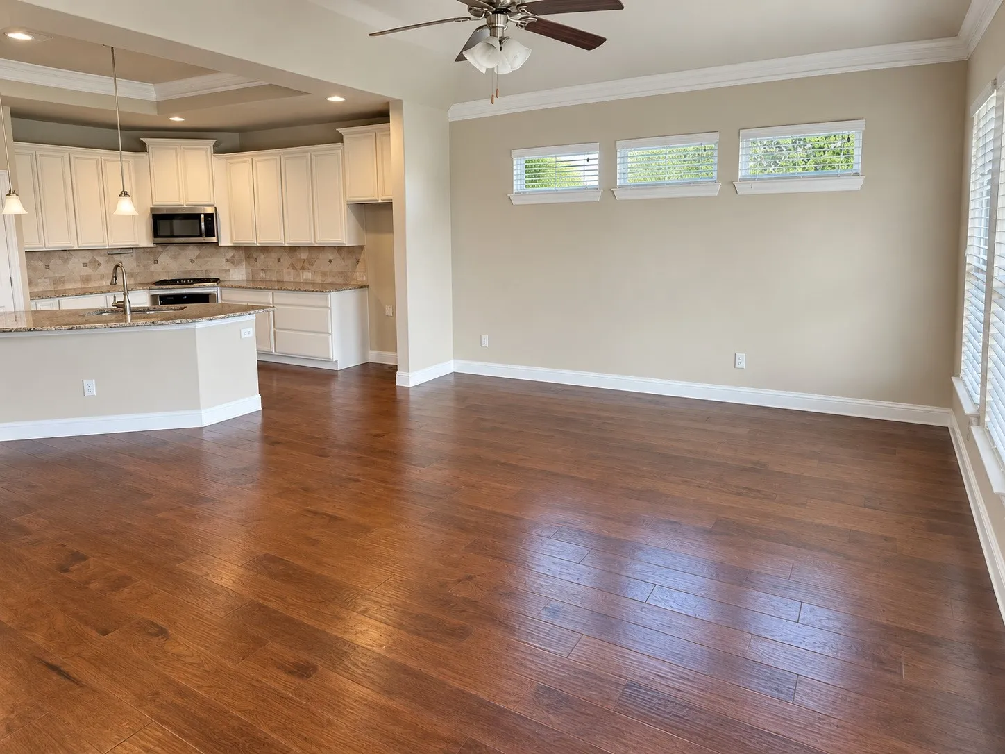 Wood-finish flooring, recessed lighting, ceiling fan, crown molding, and kitchen with granite-style countertops
