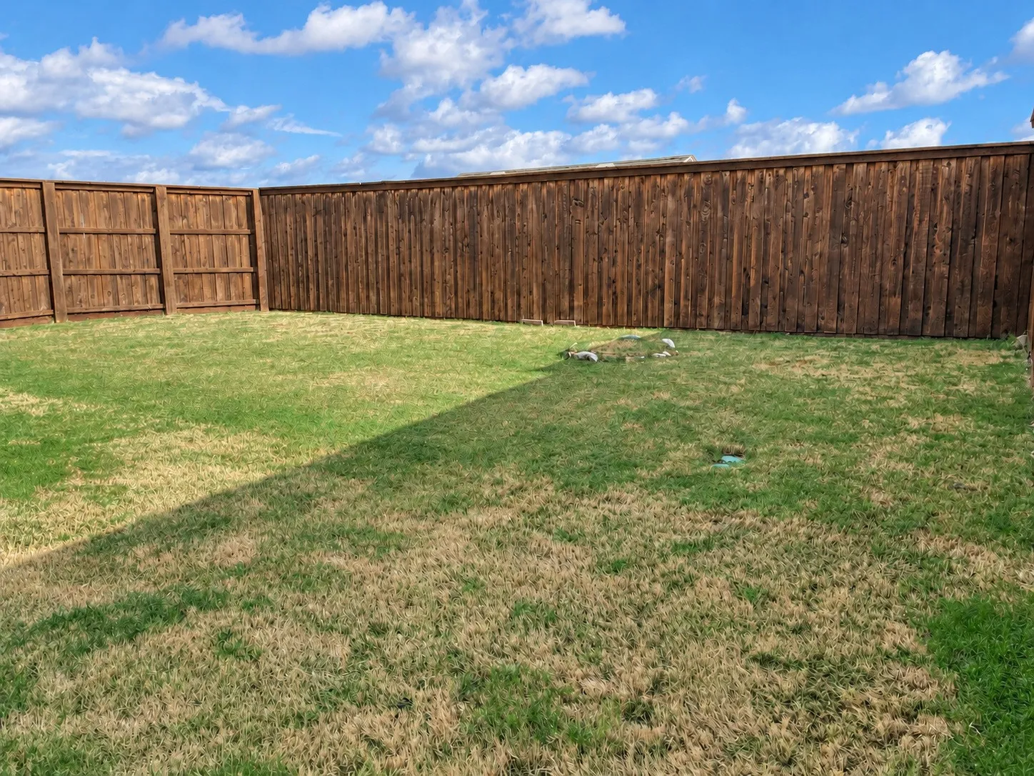 Expansive backyard featuring a natural grass lawn and wood privacy fencing