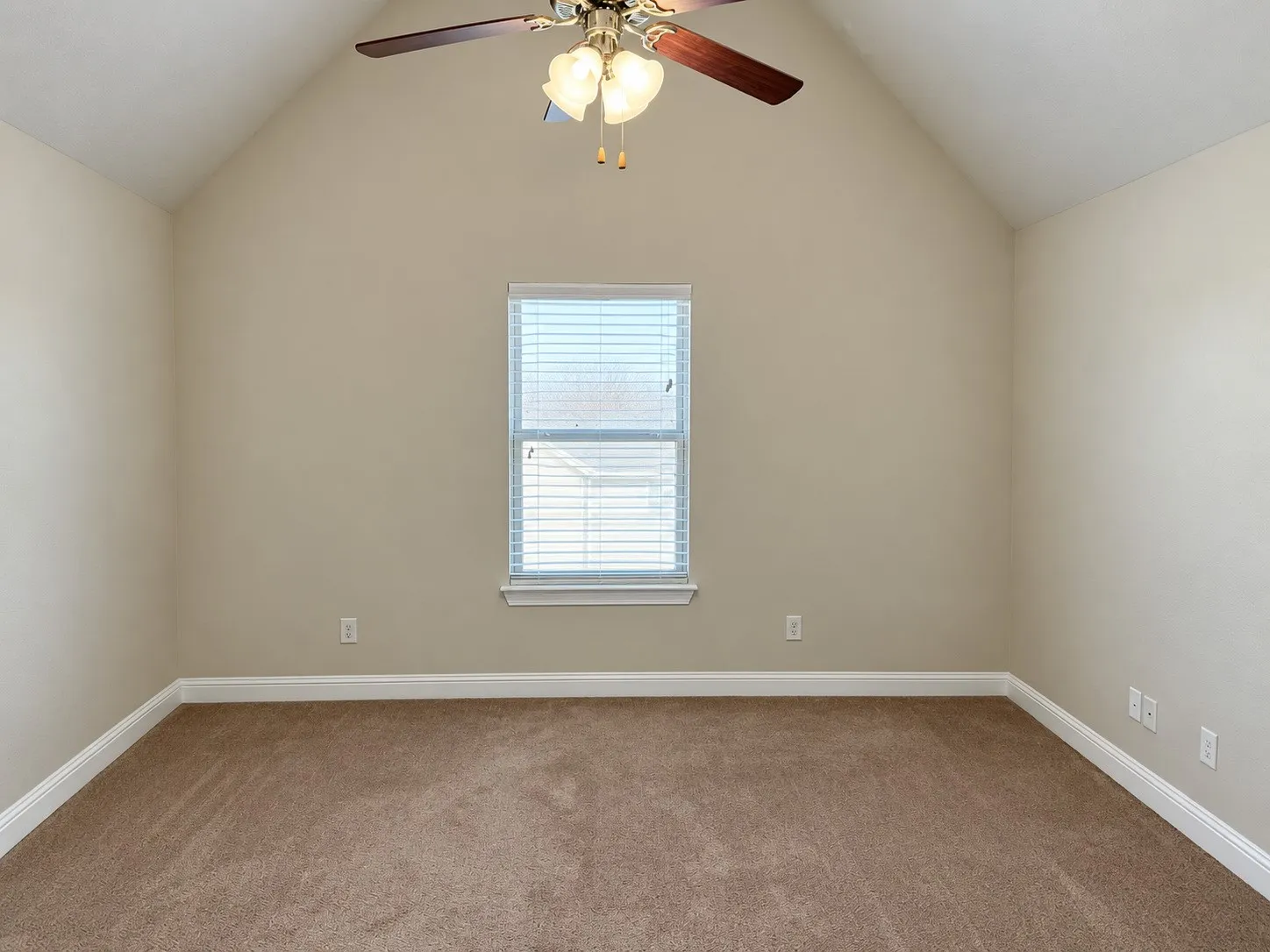 Vaulted ceiling with a ceiling fan, neutral wall paint, and carpeted flooring